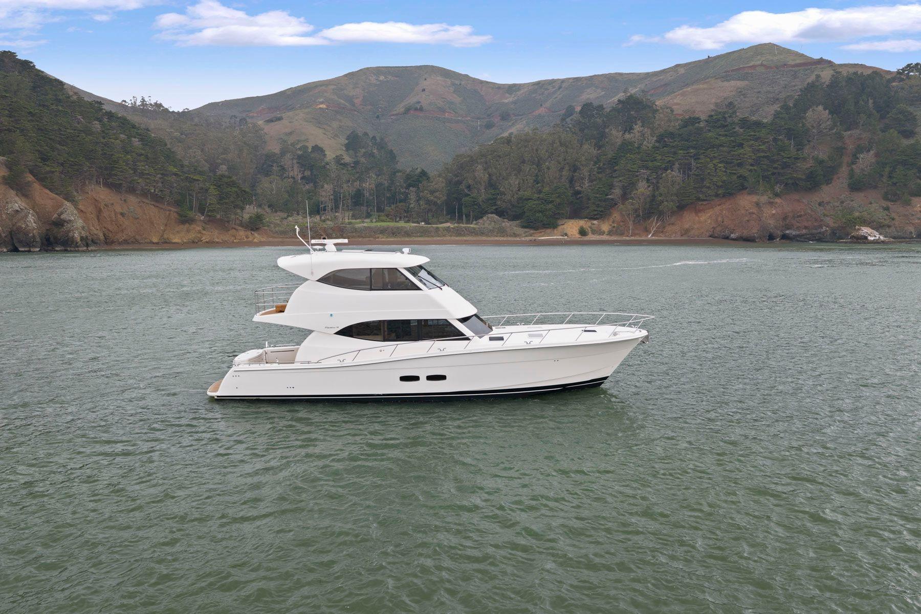 2014 Maritimo M50 yacht cruising on a scenic lake with mountainous backdrop.