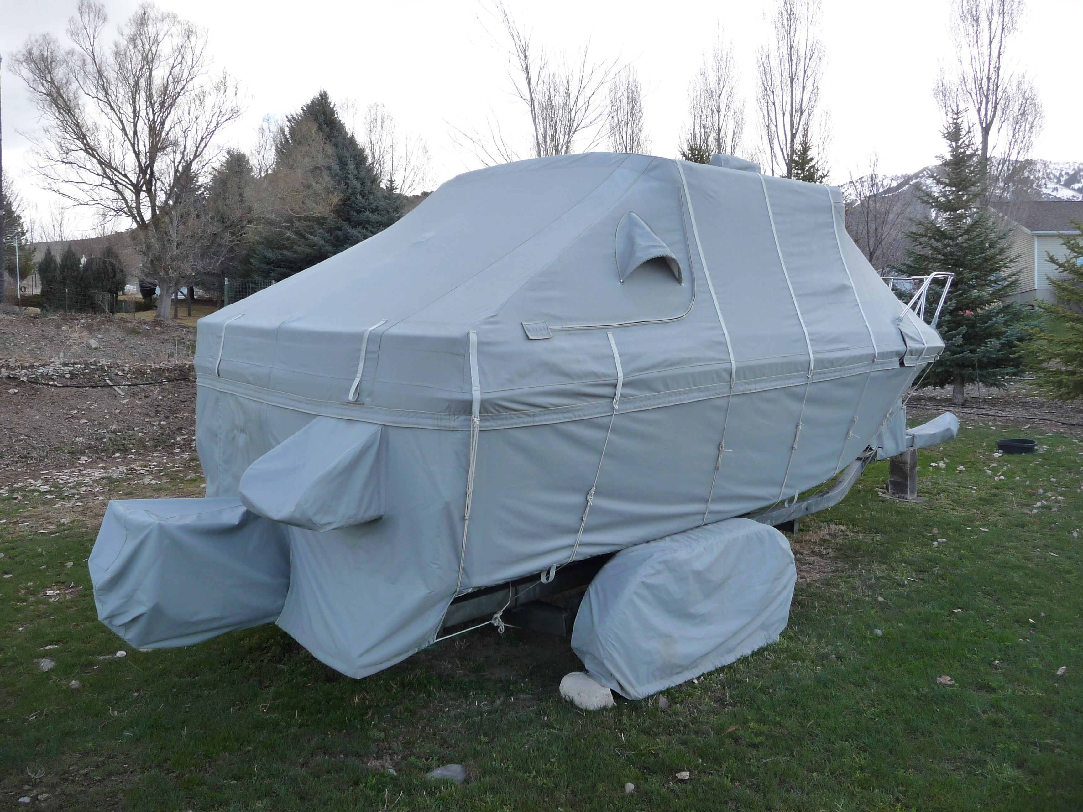 A 1991 Bayliner 2159 is covered with a gray tarp and sits on a trailer.