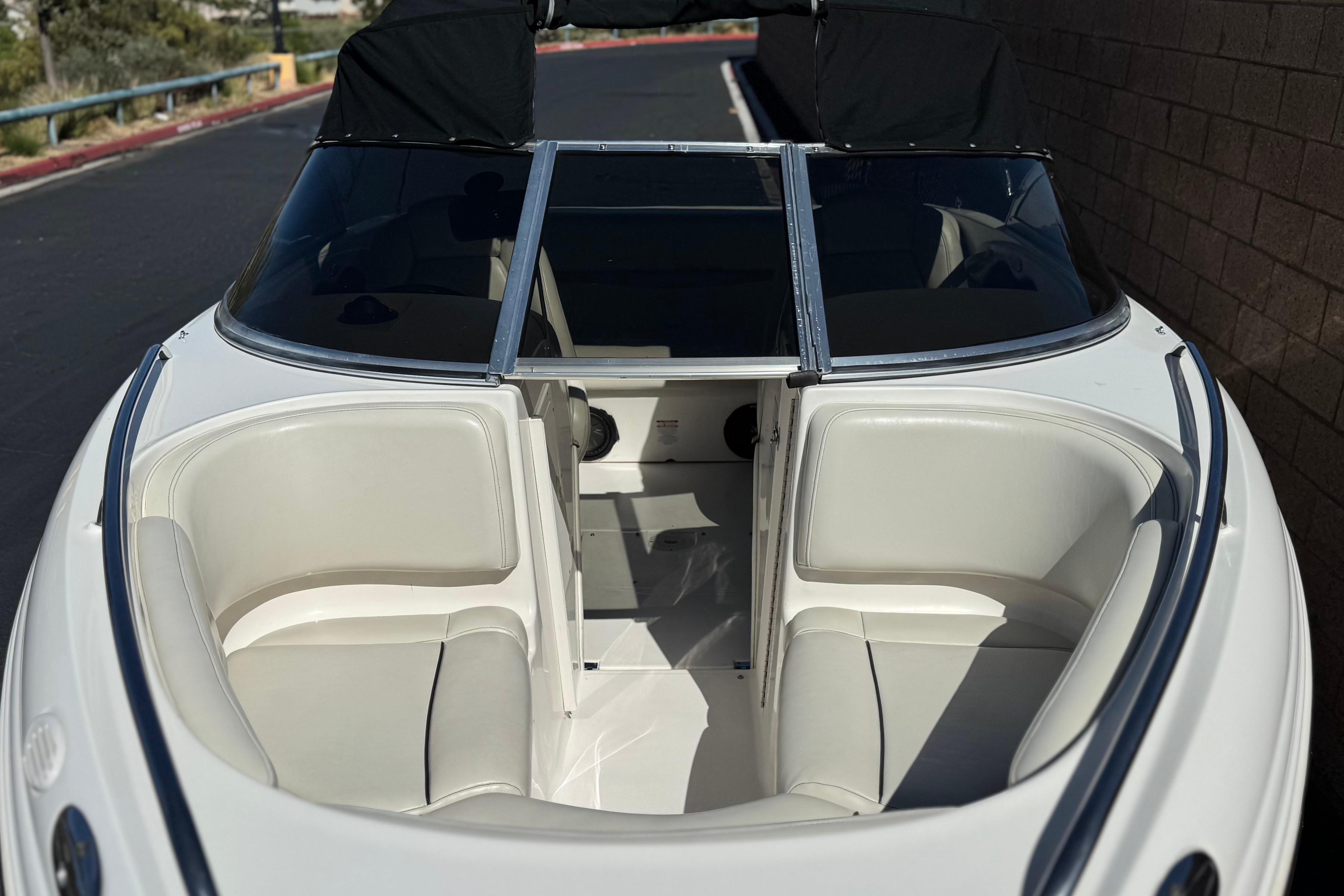 2002 Chaparral 186 SSi boat with white seating and black canopy, docked outdoors.