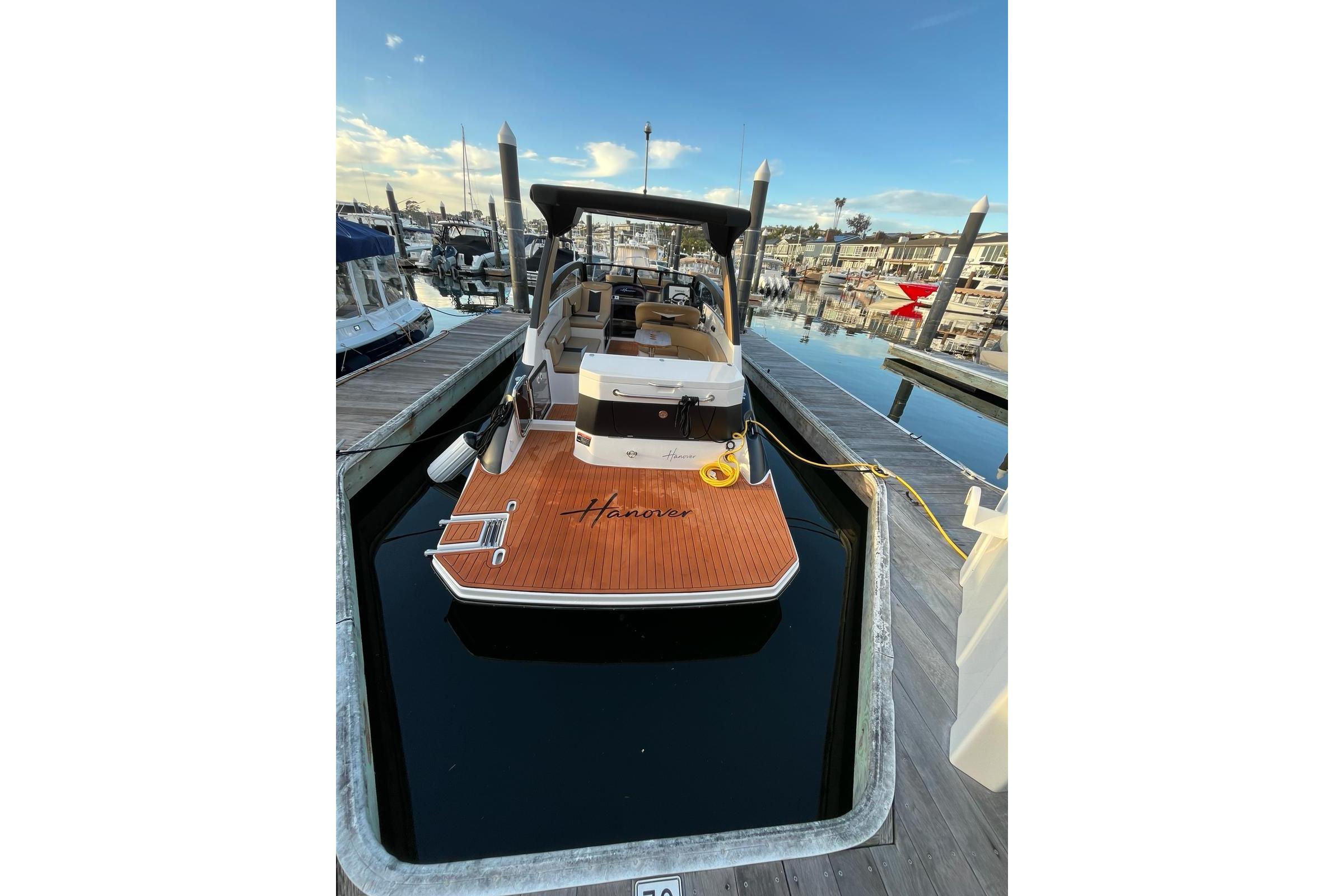 2026 Hanover 305 boat docked at marina, featuring sleek design and wooden deck.