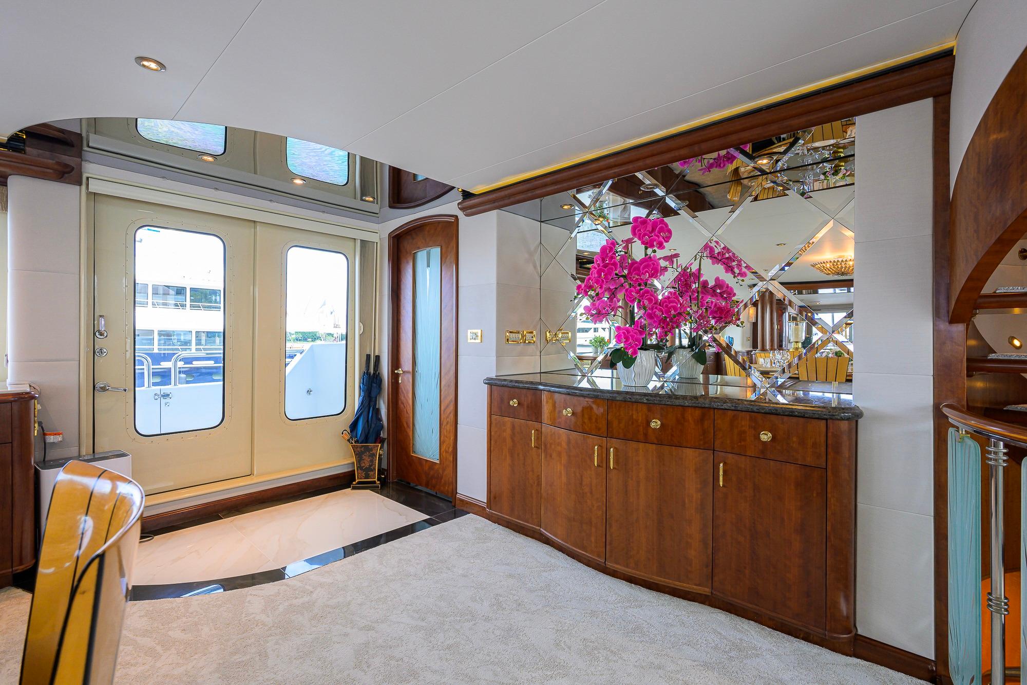 Luxurious interior of 2003 Cheoy Lee Trideck yacht with elegant wood cabinetry and floral decor.