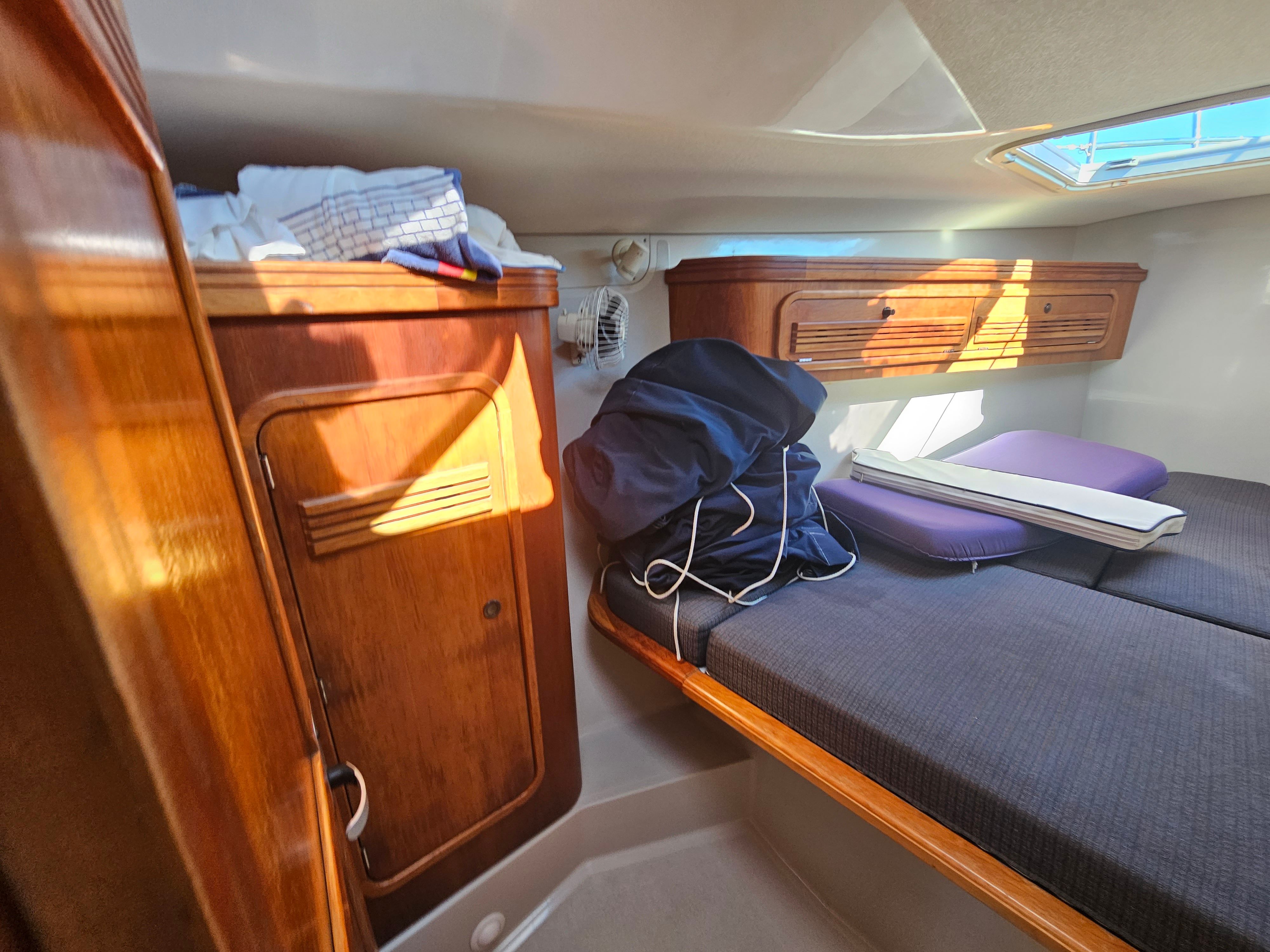Cozy cabin interior of 1967 Jensen Cal 36 sailboat with wooden storage and bedding.