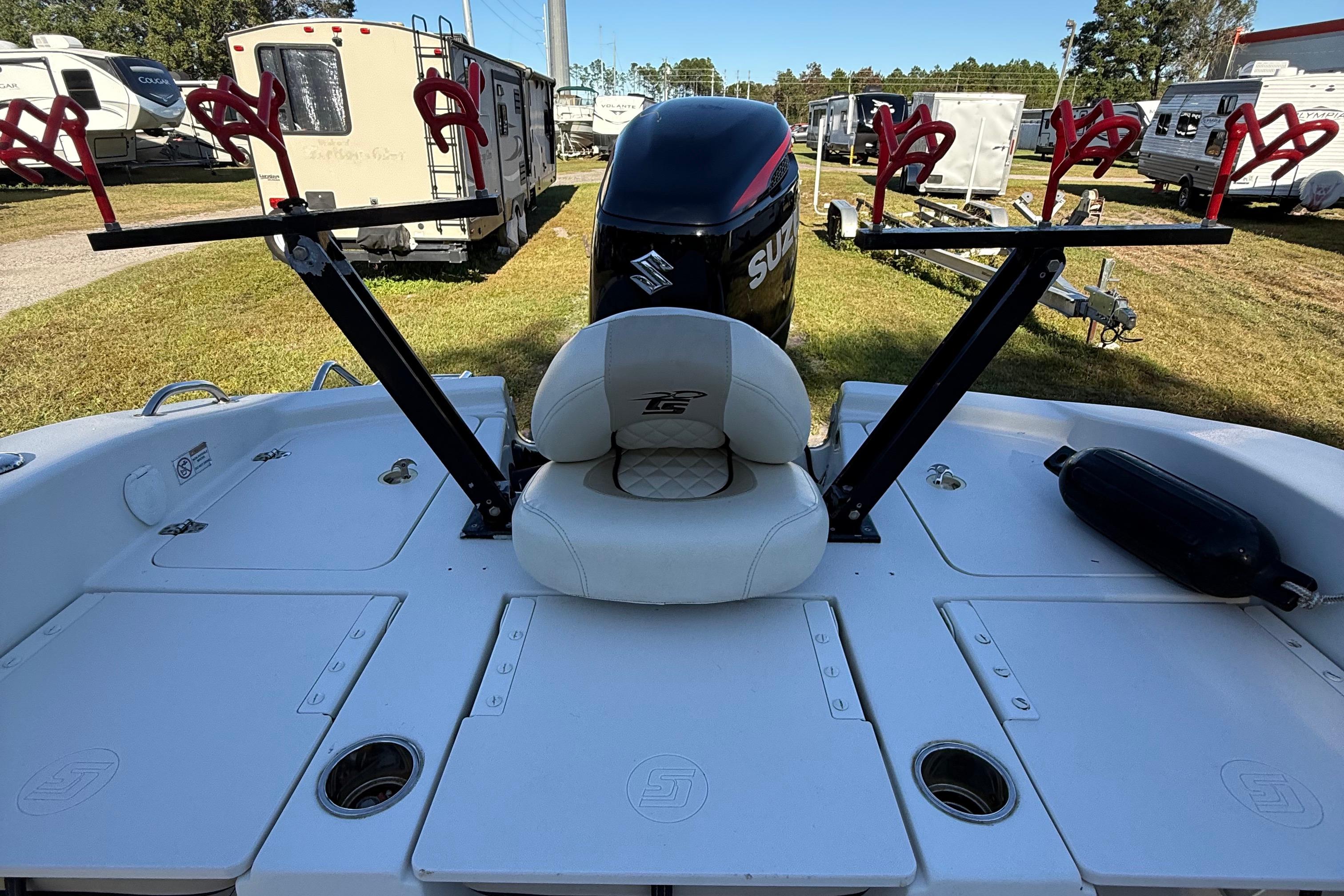 2021 Carolina Skiff 26 Ultra Elite boat with Suzuki engine and rod holders, parked near RVs.