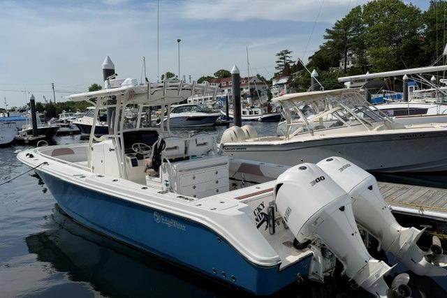 2014 Edgewater 318CC boat docked, featuring dual engines and a sleek blue hull.