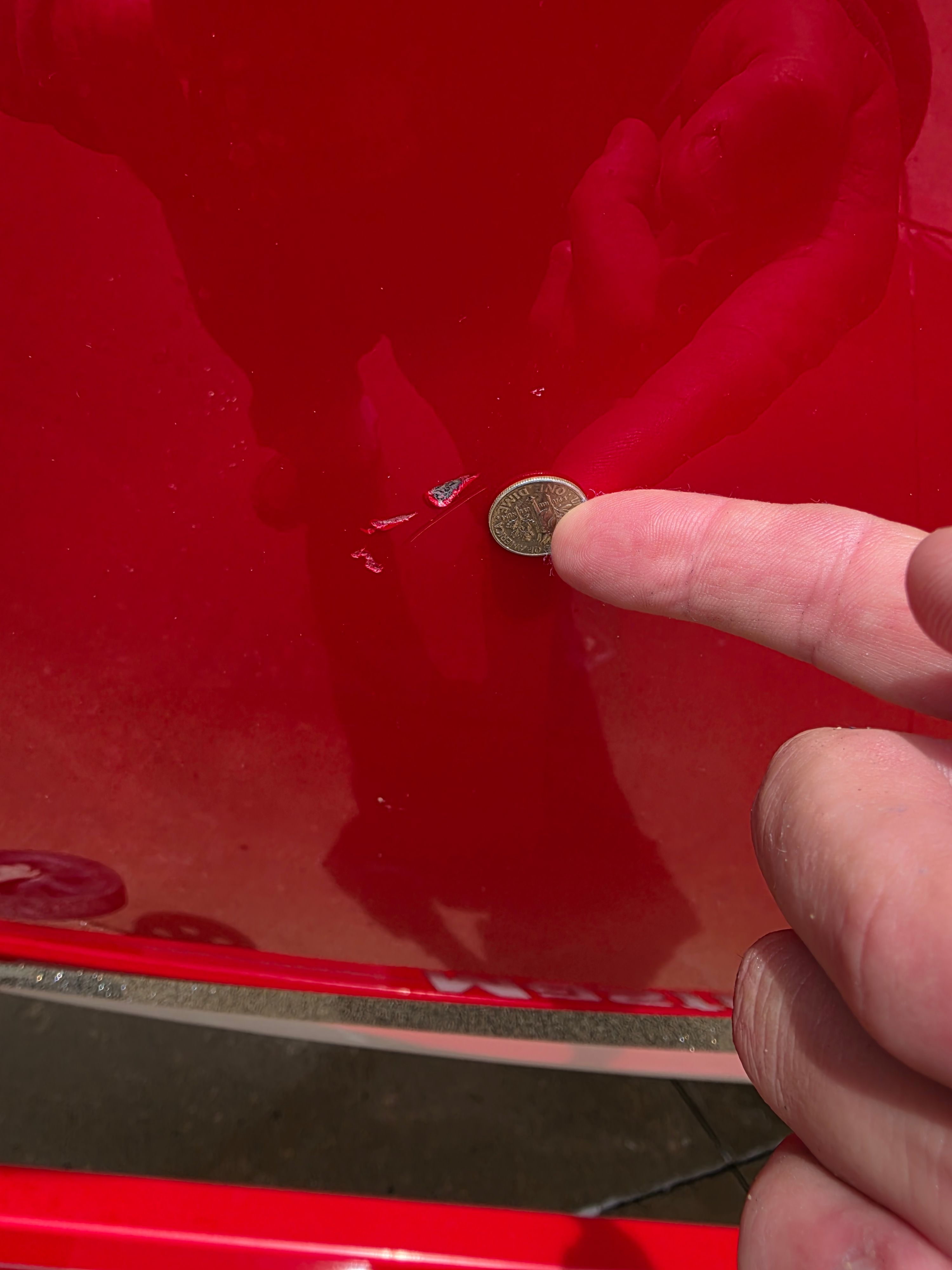 Close-up of a scratch on a red 2007 MasterCraft X-15 boat.