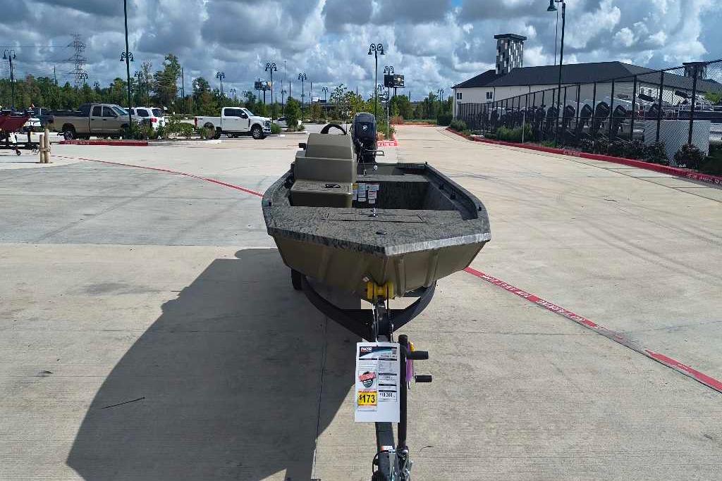 2026 Tracker Grizzly 1648 SC boat on trailer in parking lot, cloudy sky background.