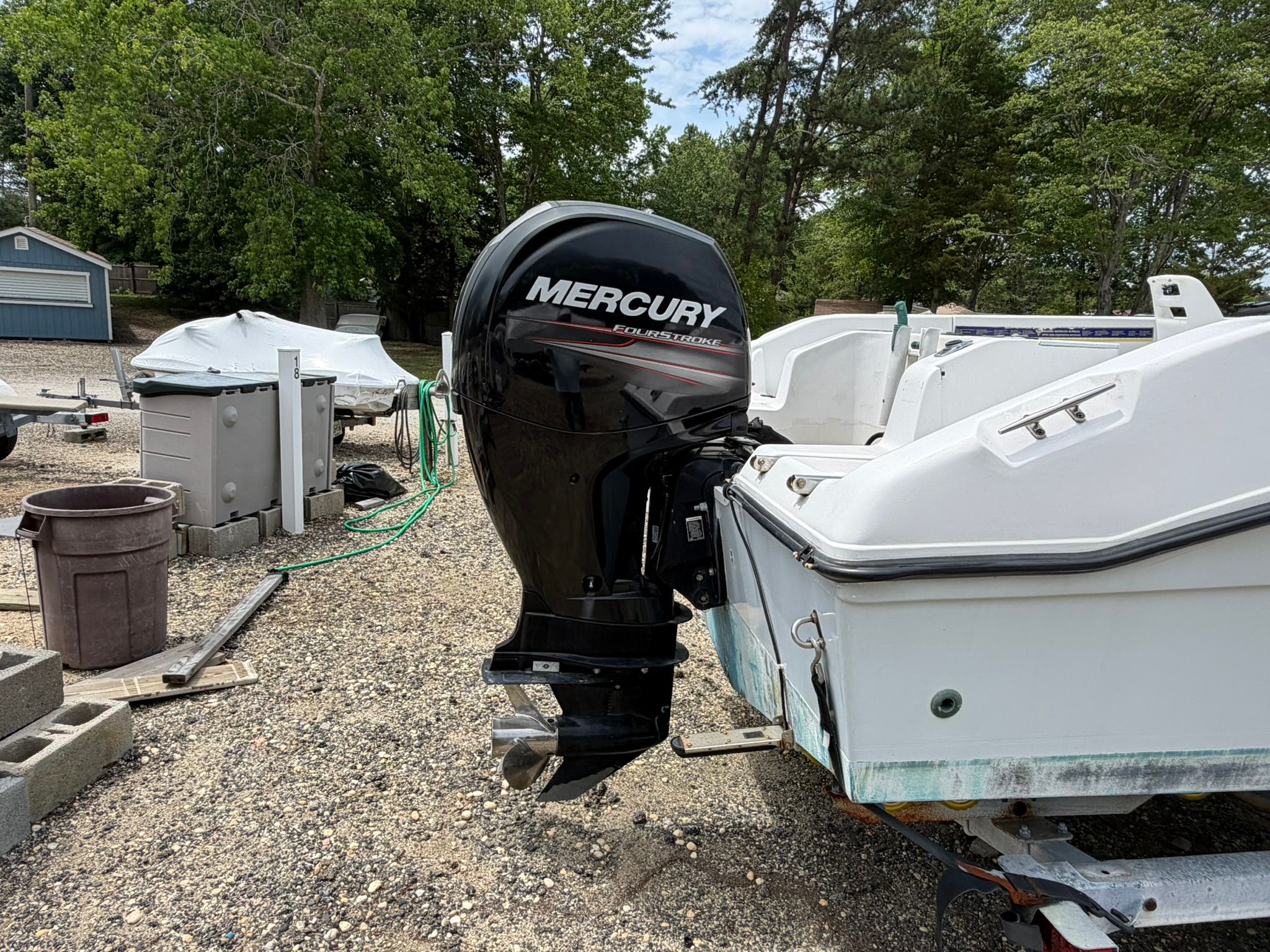 An Angler boat with a Mercury outboard motor is on a gravel lot.