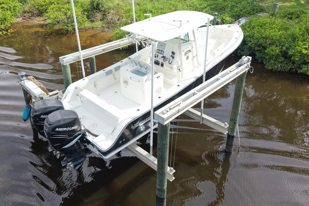 2018 Mako 284 Center Console boat on lift, featuring dual Mercury engines.
