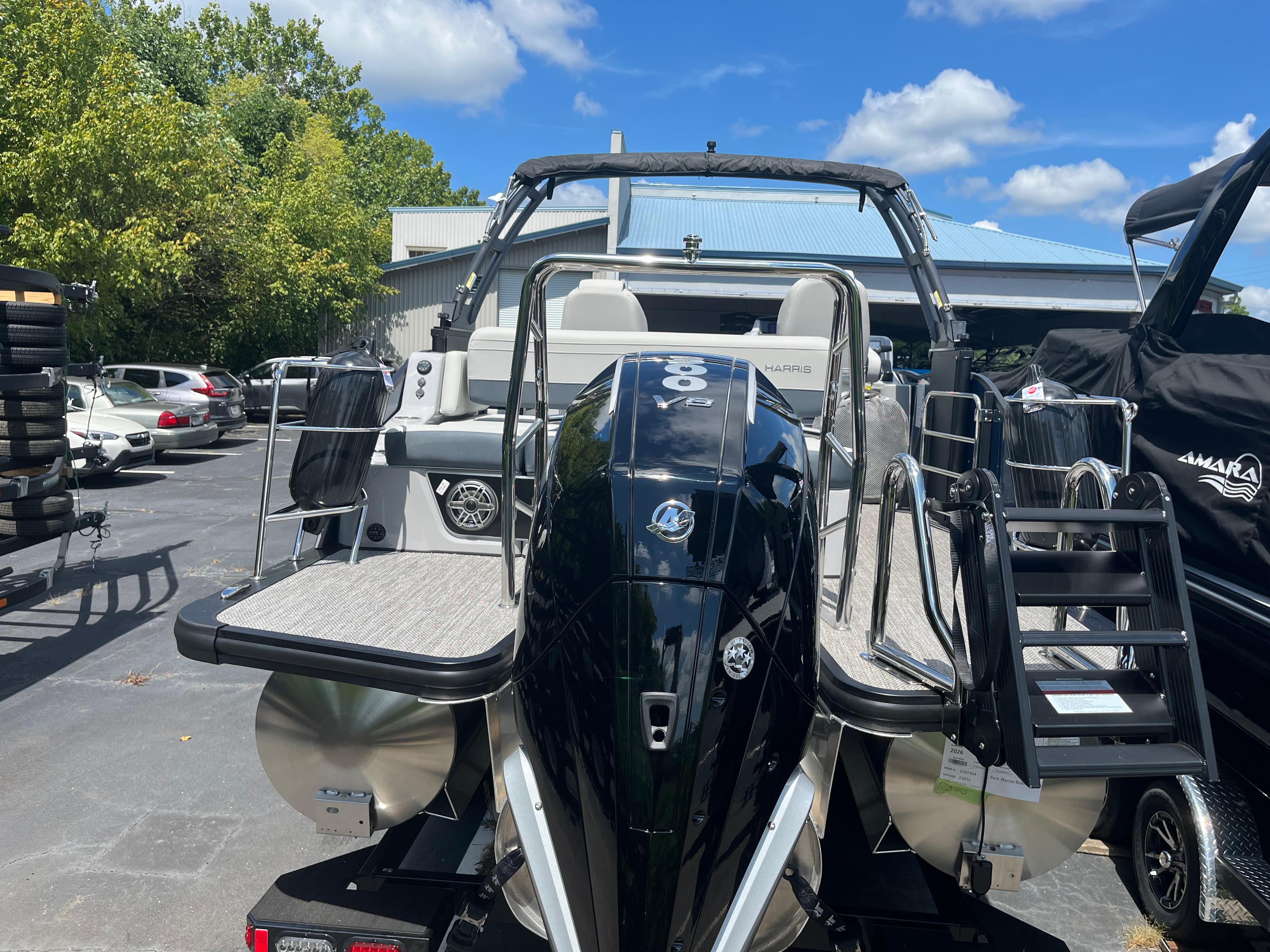 2026 Harris Grand Mariner 230 boat with powerful engine, docked outdoors under blue sky.