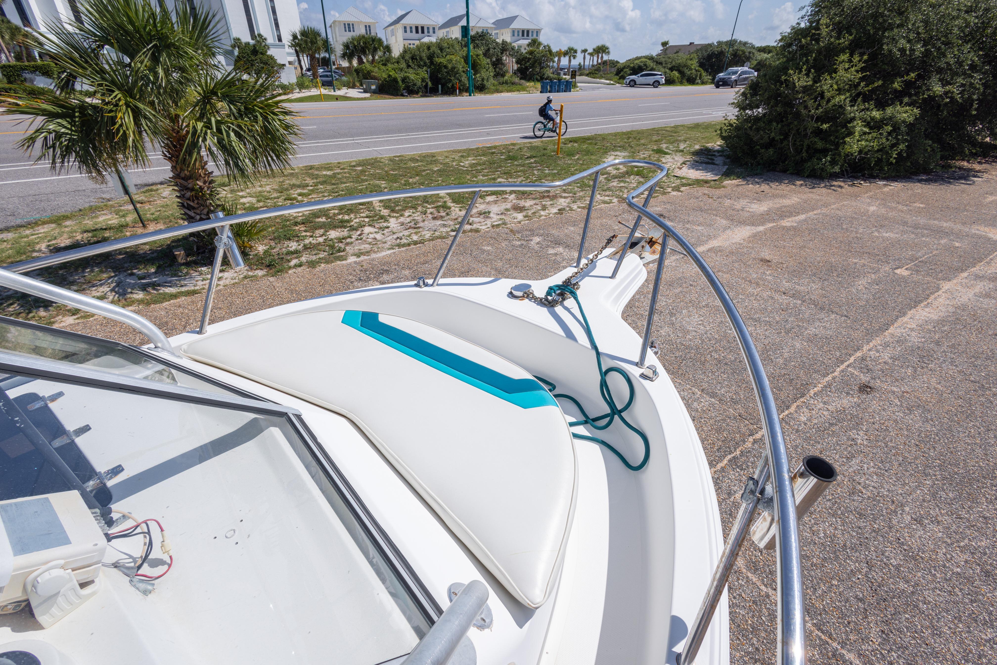 1999 Aquasport 225 Explorer boat with white deck, teal accents, and coastal background.
