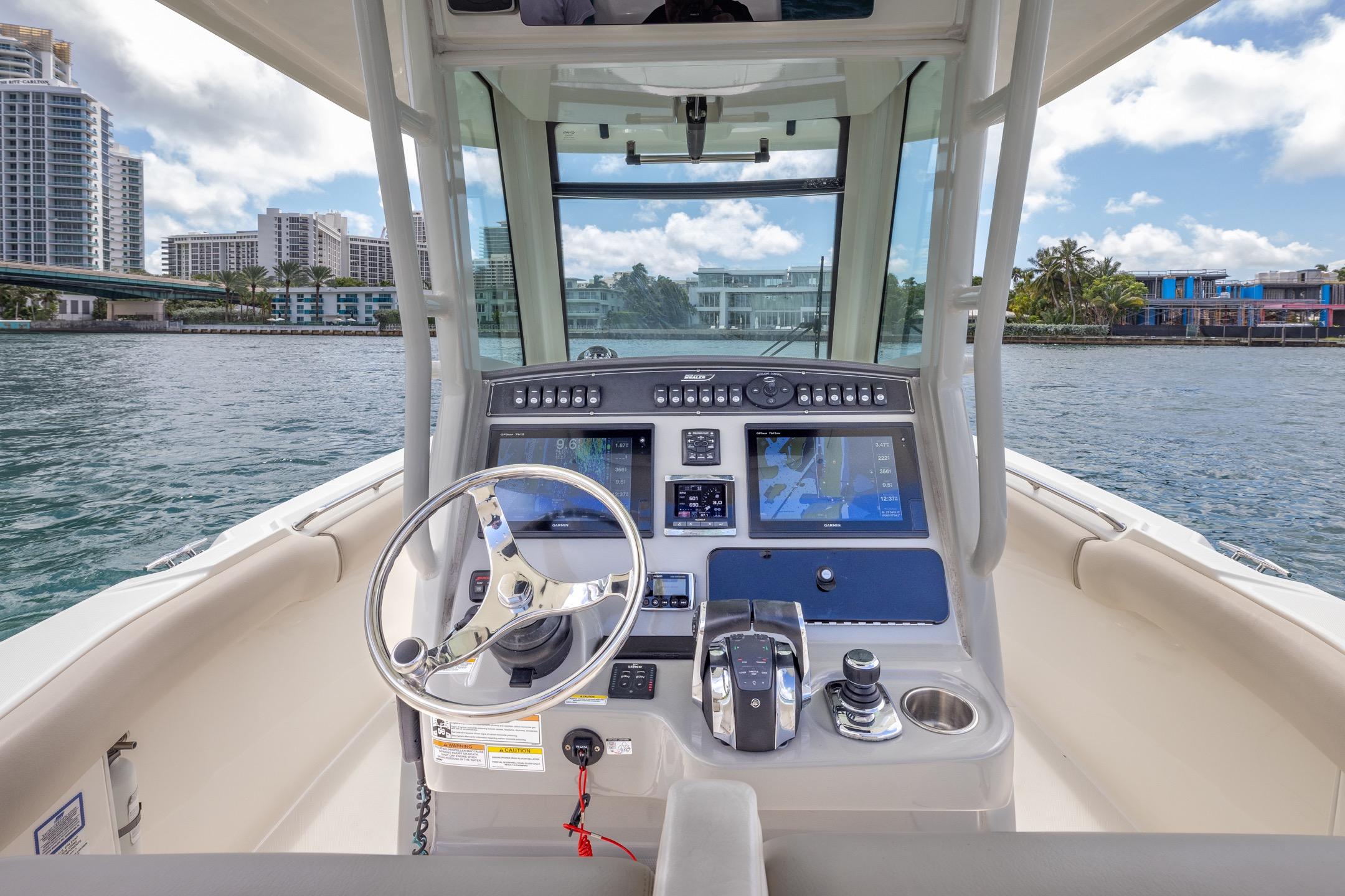 2016 Boston Whaler 280 Outrage helm with modern navigation system, docked near waterfront buildings.