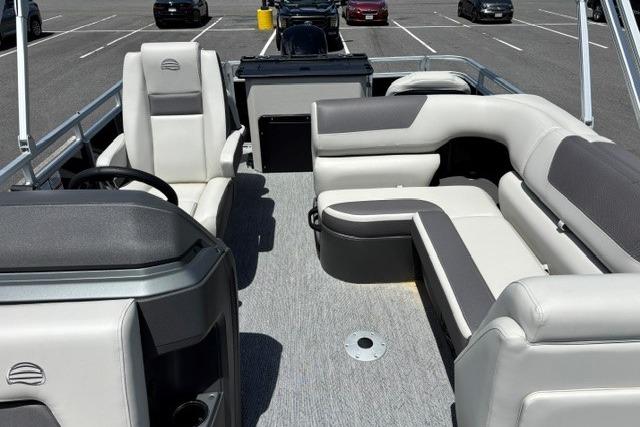 2026 Sun Tracker Fishin' Barge 20 DLX interior with plush seating in a parking lot.