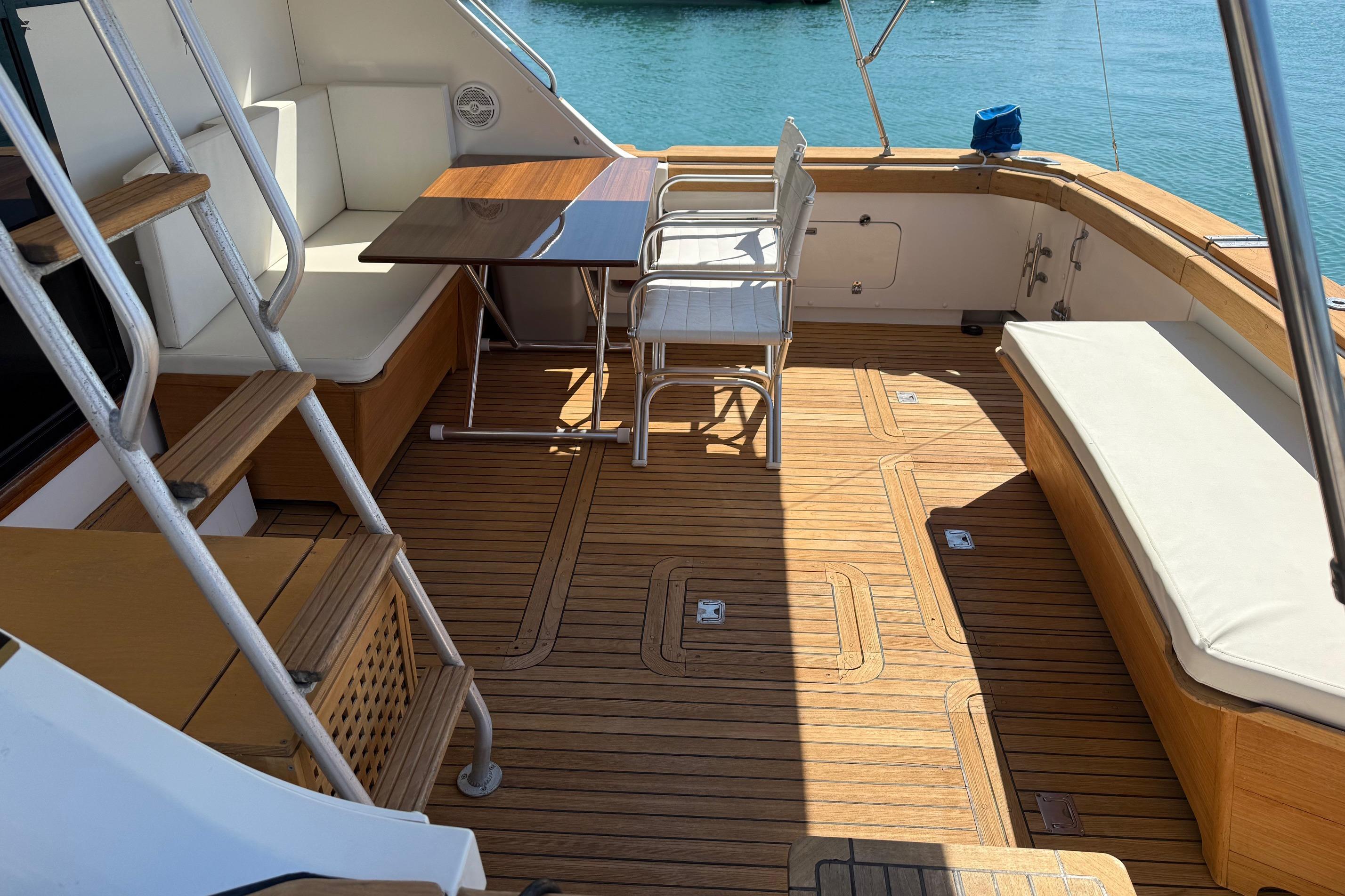 1987 Bertram 37 Convertible yacht deck with seating and table, overlooking water.
