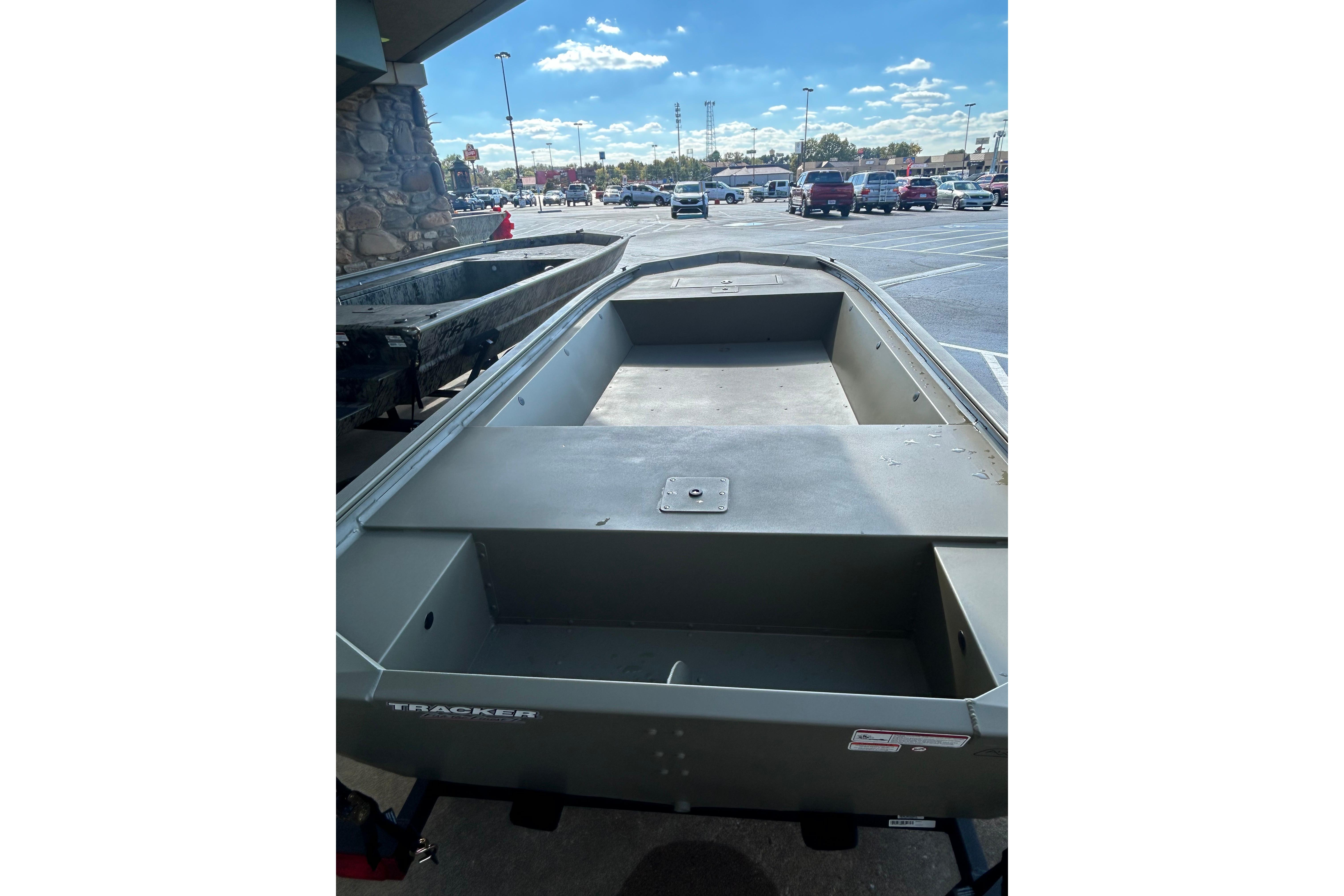2026 Tracker Grizzly 1648 Utility boat in parking lot under clear sky.