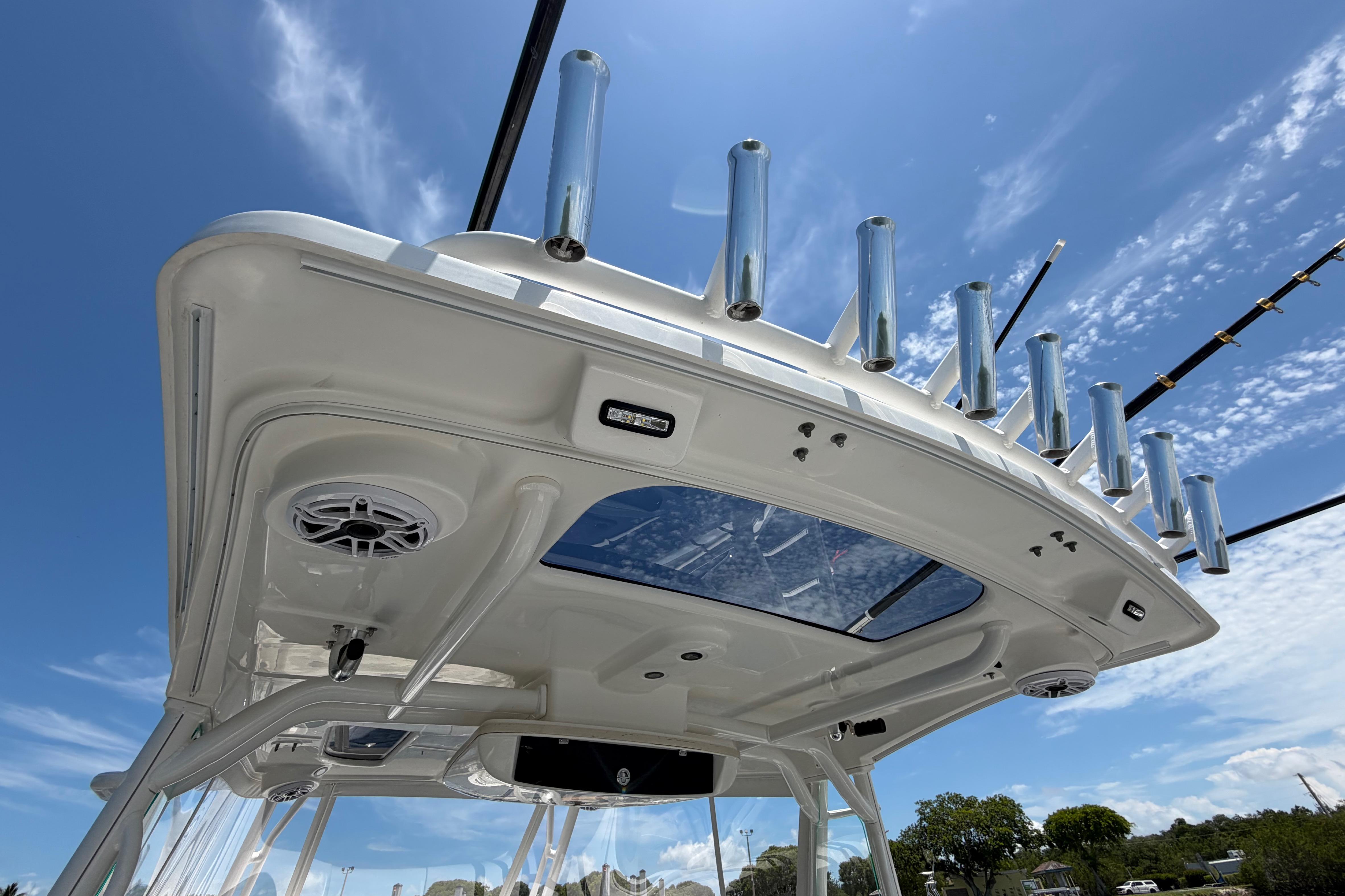 2009 Everglades 350LX boat roof with rod holders and speakers under a clear blue sky.