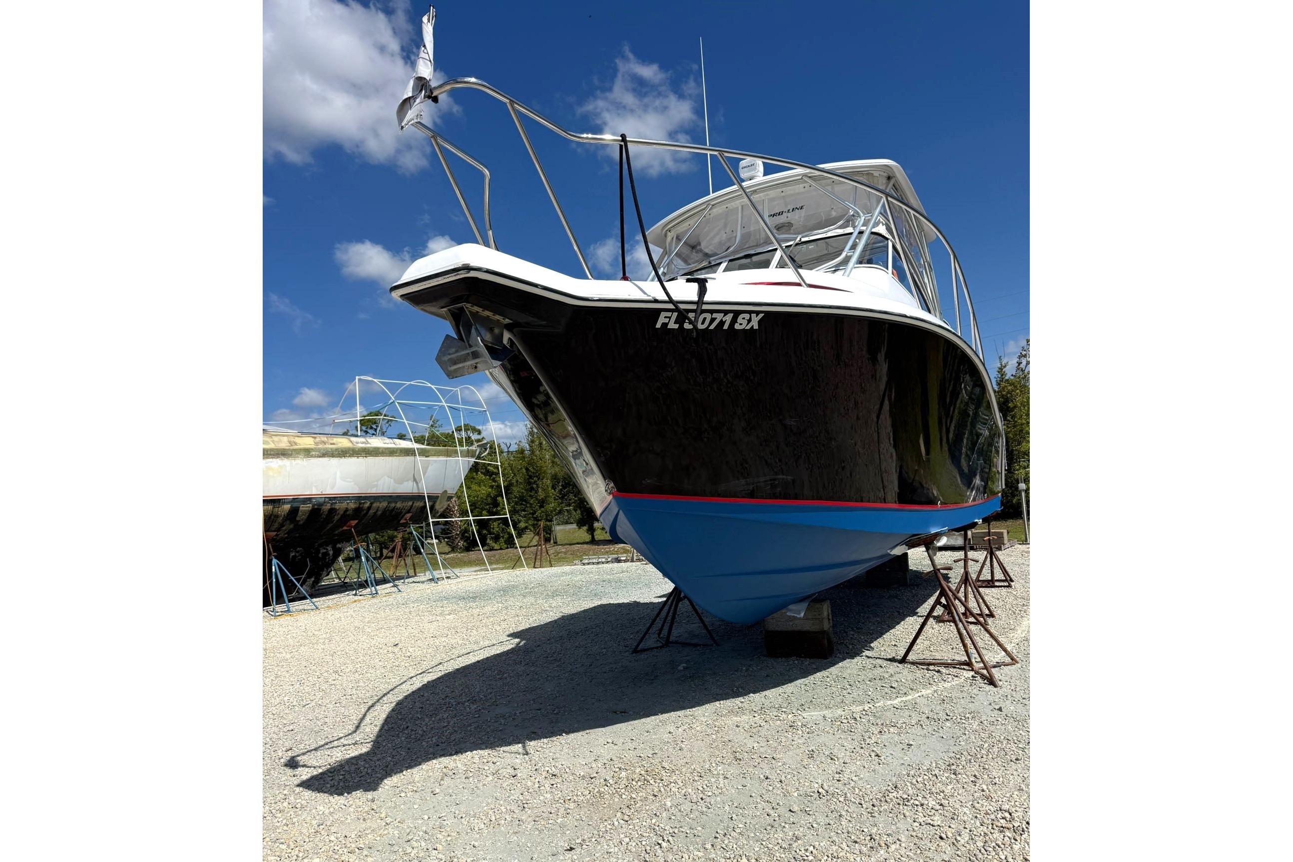 2006 Pro-Line 32 Express boat on stands, under clear blue sky.
