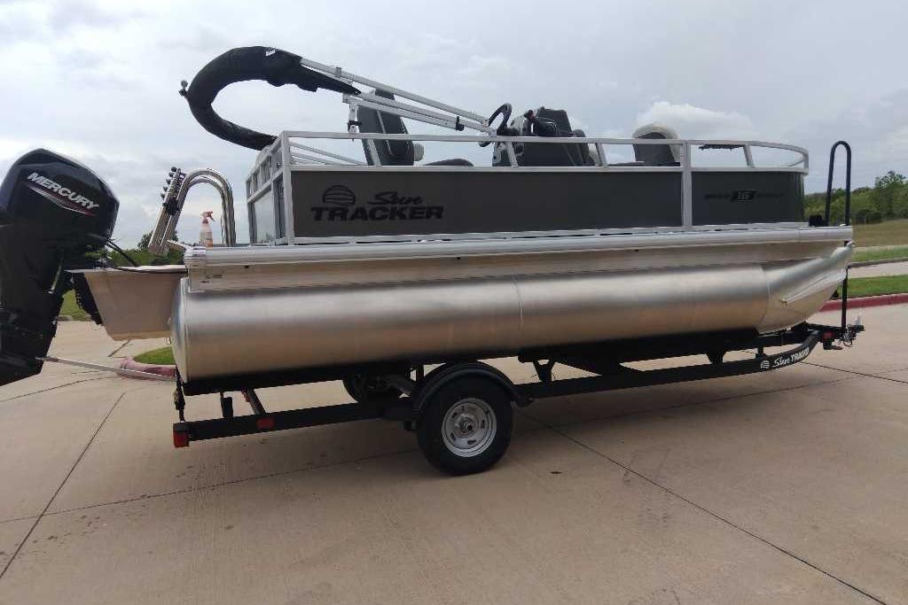 2026 Sun Tracker Bass Buggy 16 XL Select pontoon boat on trailer, featuring Mercury outboard motor.