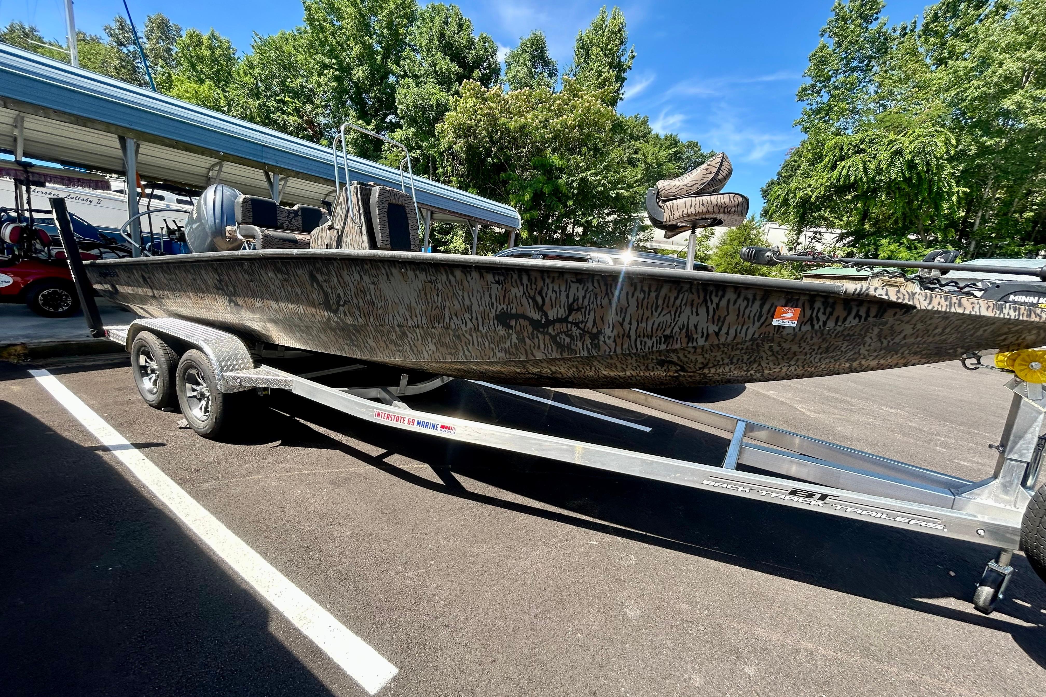 2025 Xpress H22B Bay boat on trailer, parked outdoors under clear blue sky.