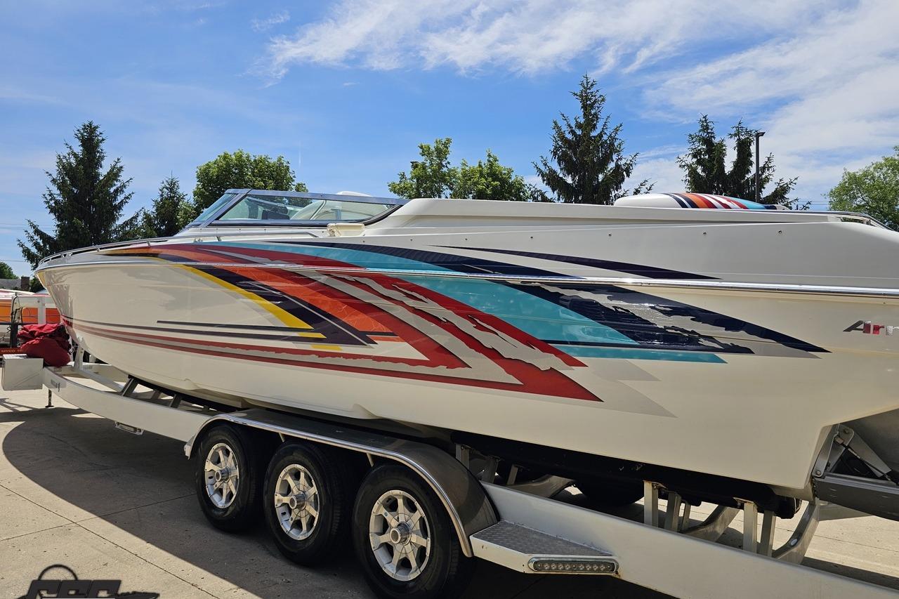 2002 Formula 382 FASTech speedboat with colorful graphics on a trailer, under a clear sky.