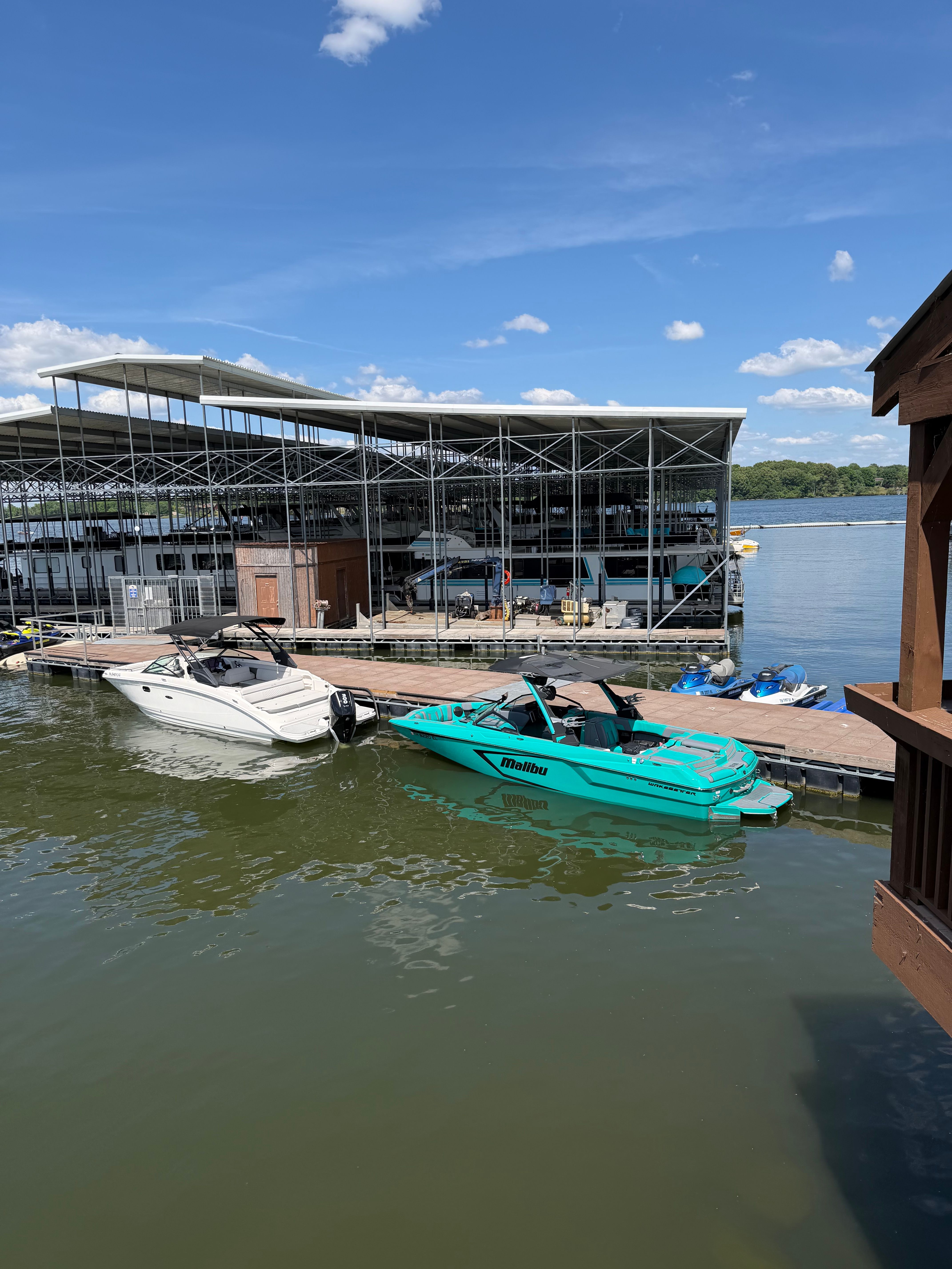 A turquoise Malibu Wakesetter 24 MXZ is docked next to a white boat.