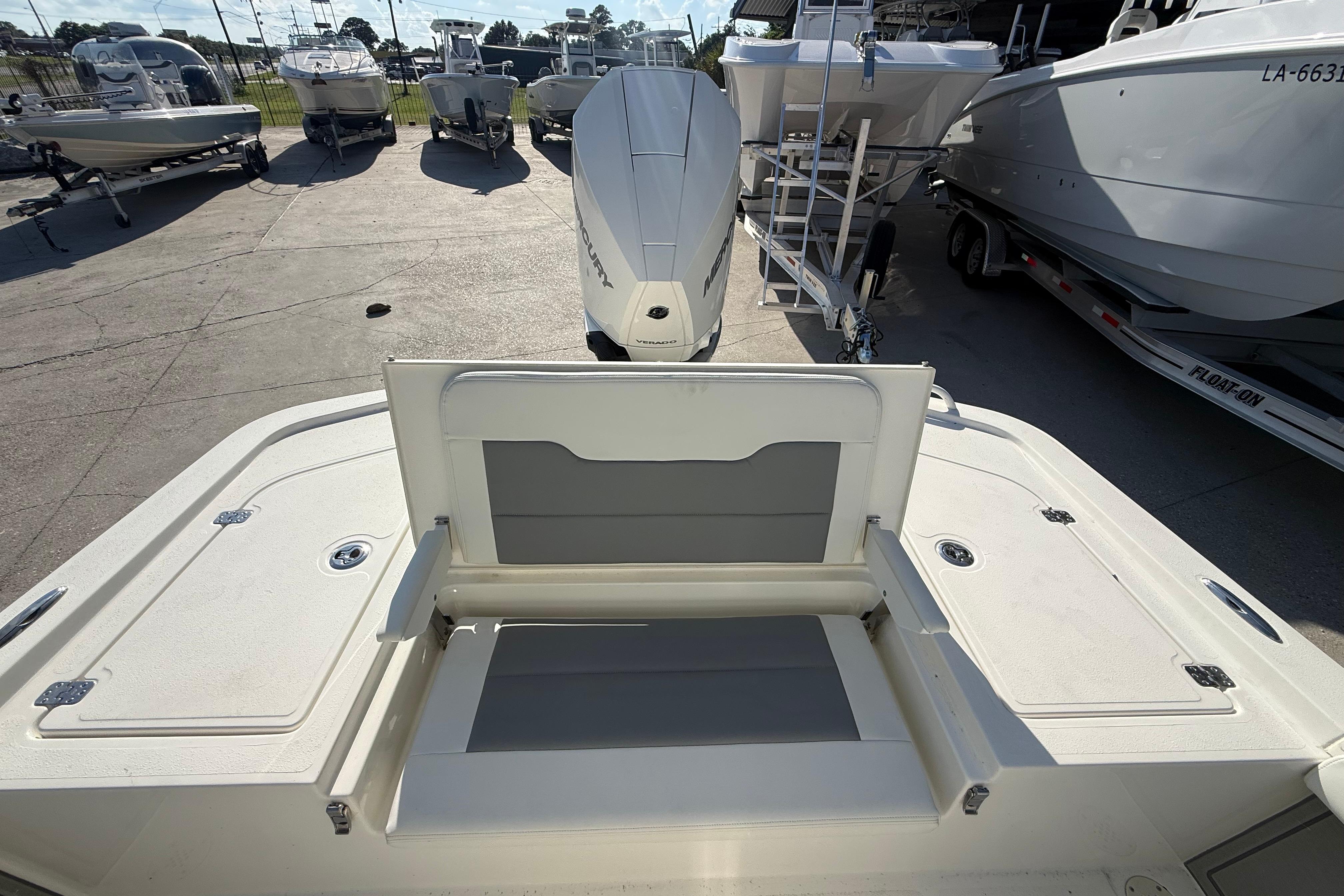 2026 Mako 24 APEX boat with open storage compartment, parked among other boats.