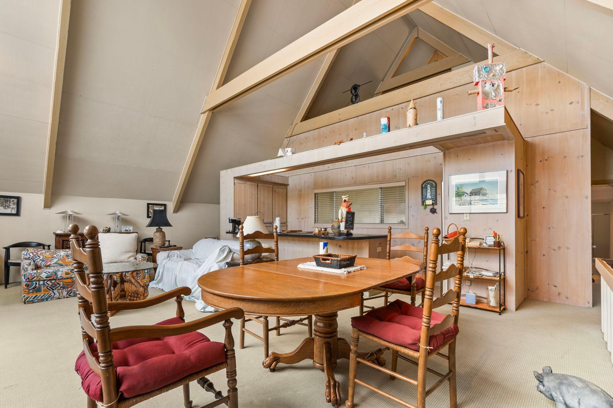 Spacious 1976 custom boathouse interior with wooden beams, dining area, and cozy seating.