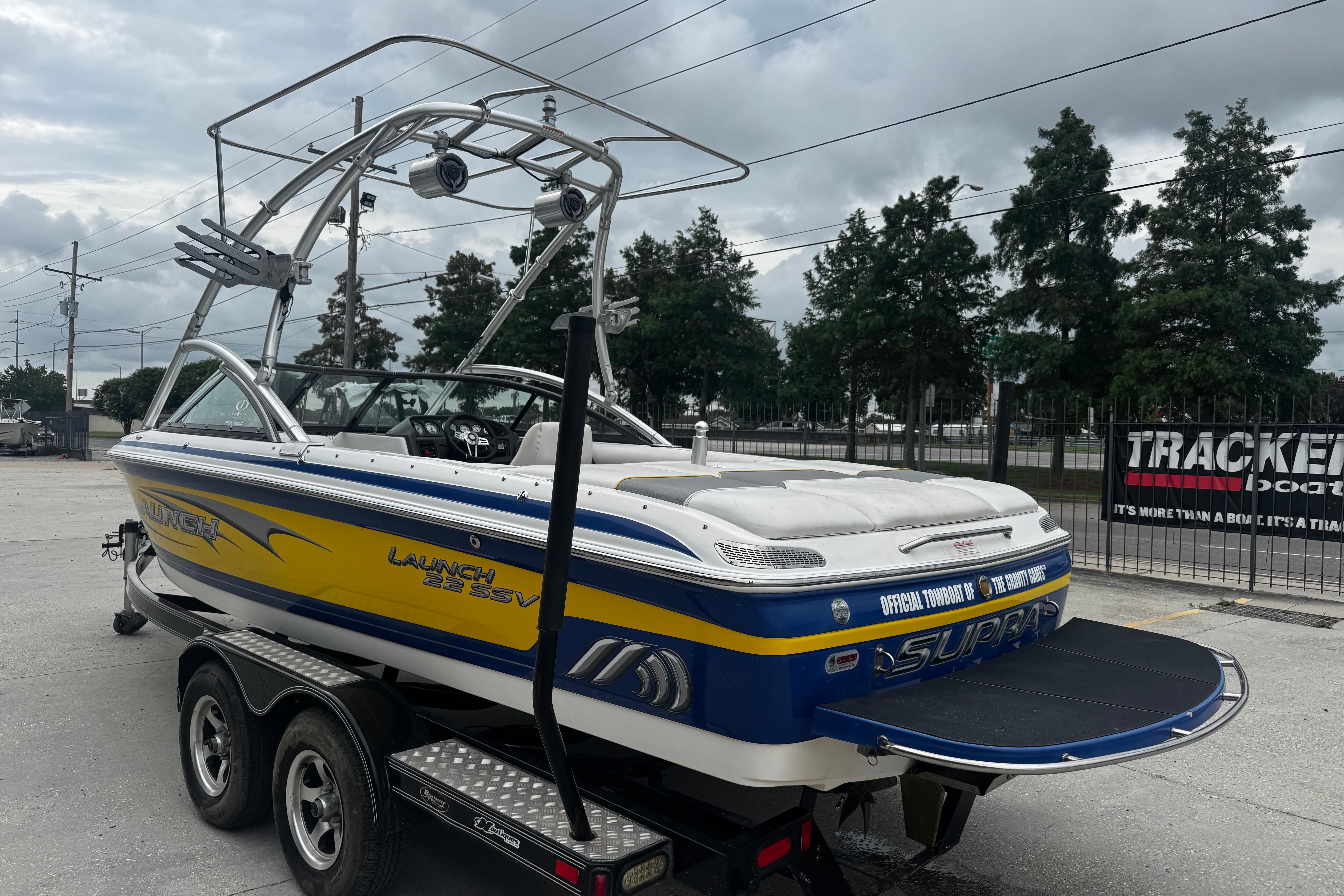 2006 Supra Launch 22 SSV boat on trailer, featuring vibrant yellow and blue design.