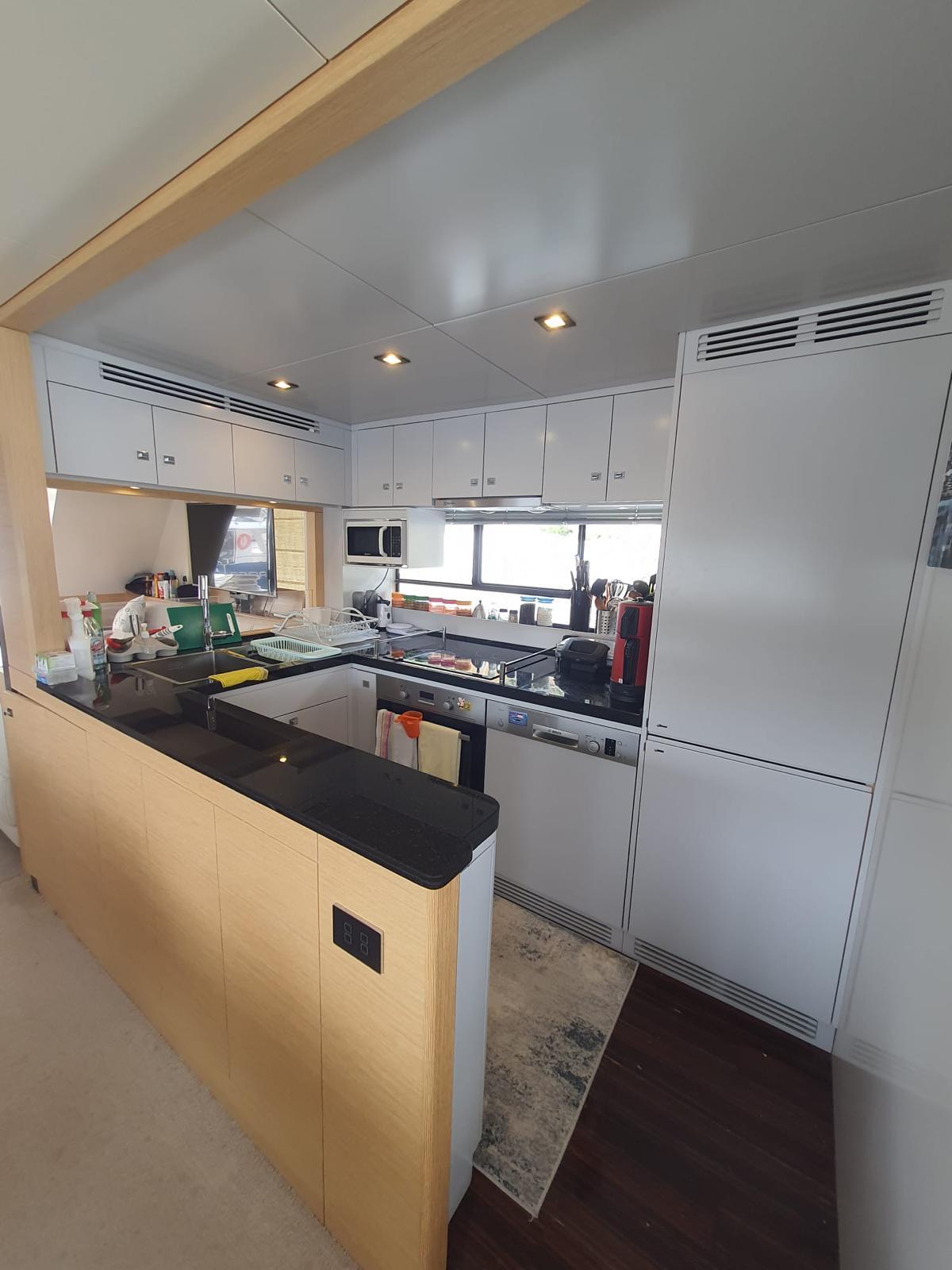 Modern kitchen interior on a 2017 Sirena 64 yacht, featuring sleek cabinetry and appliances.
