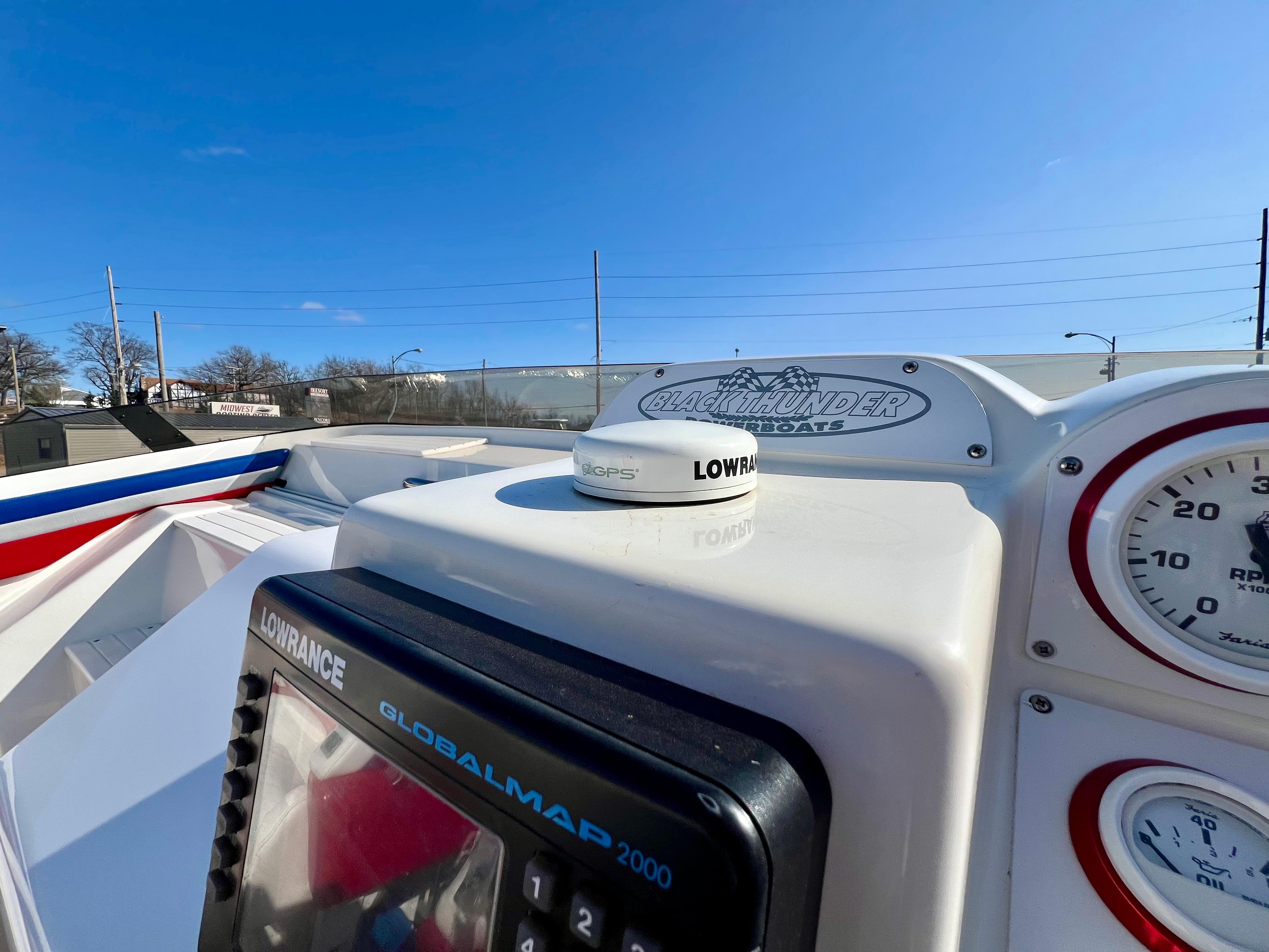 1999 Black Thunder 430 Flat Deck boat dashboard with Lowrance GPS and gauges under clear blue sky.