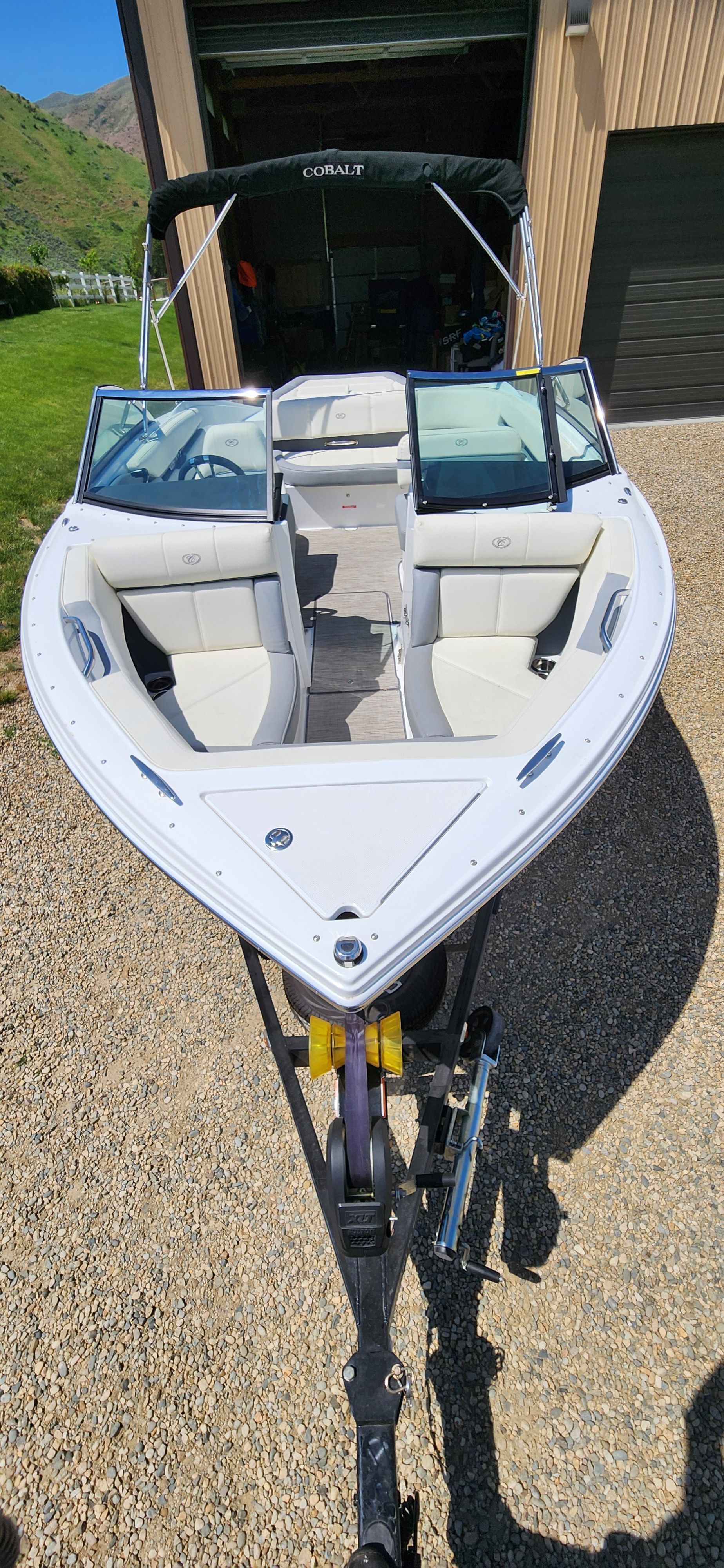 A Cobalt CS22 boat is on a trailer in front of a garage.