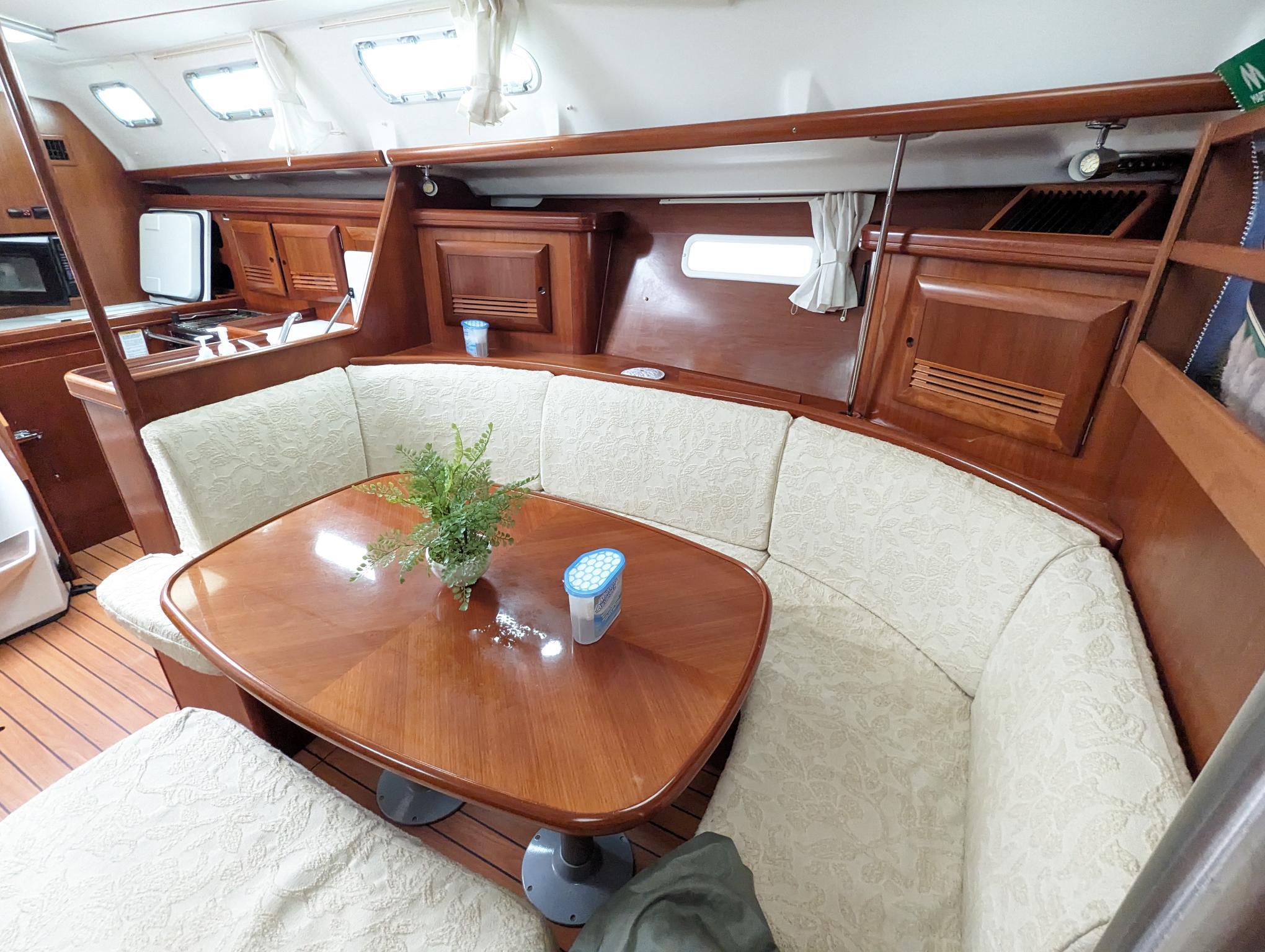 Interior of 2005 Beneteau 393 yacht with cozy dining area and wooden furnishings.