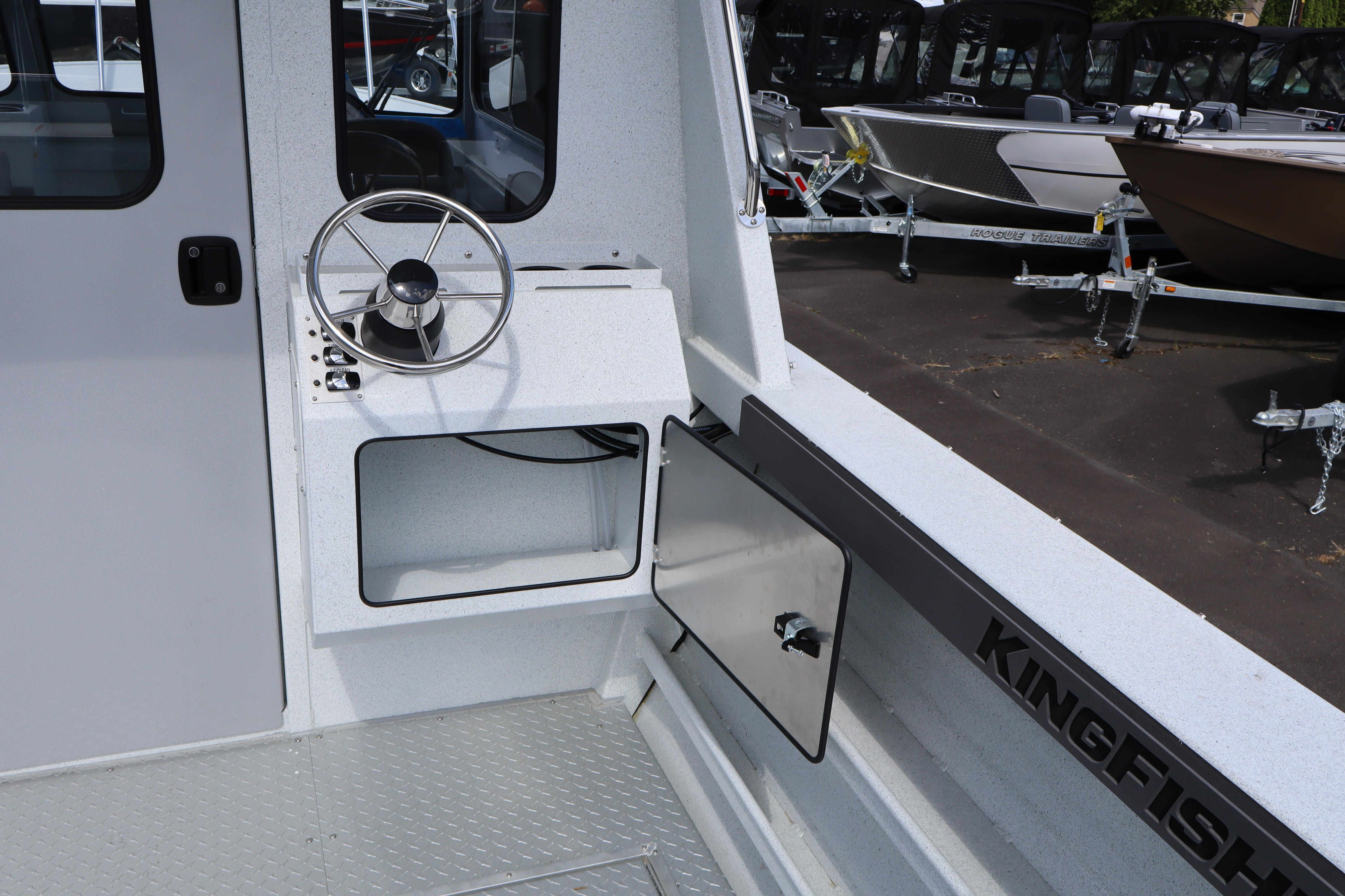 Interior view of 2026 KingFisher 2425 Escape HT boat with steering wheel and storage compartment.