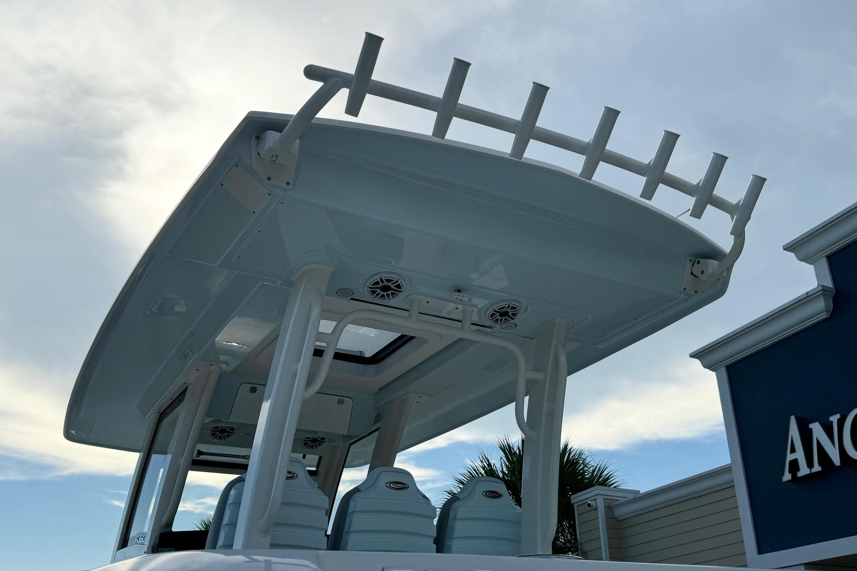 2025 Robalo R360 Center Console boat with T-top and rod holders against a cloudy sky.