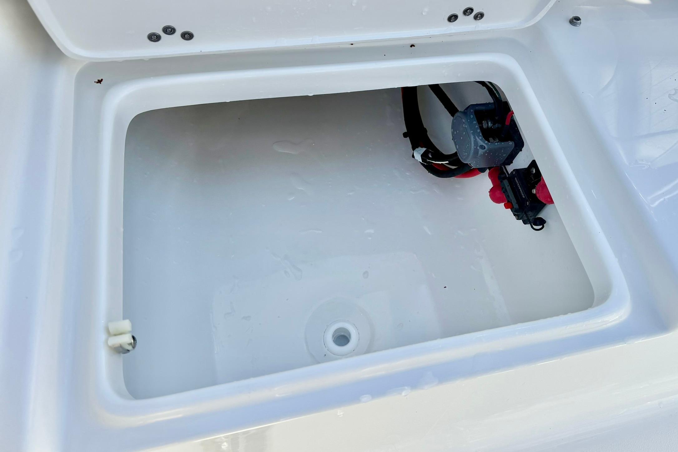 Open storage compartment in 2026 Key West 189 FS boat, featuring wiring and drainage.