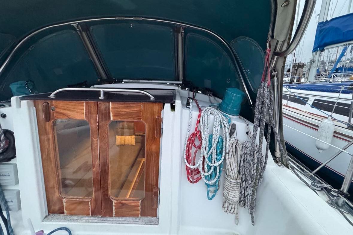 The cockpit of a sailboat with wooden doors and ropes on the side.