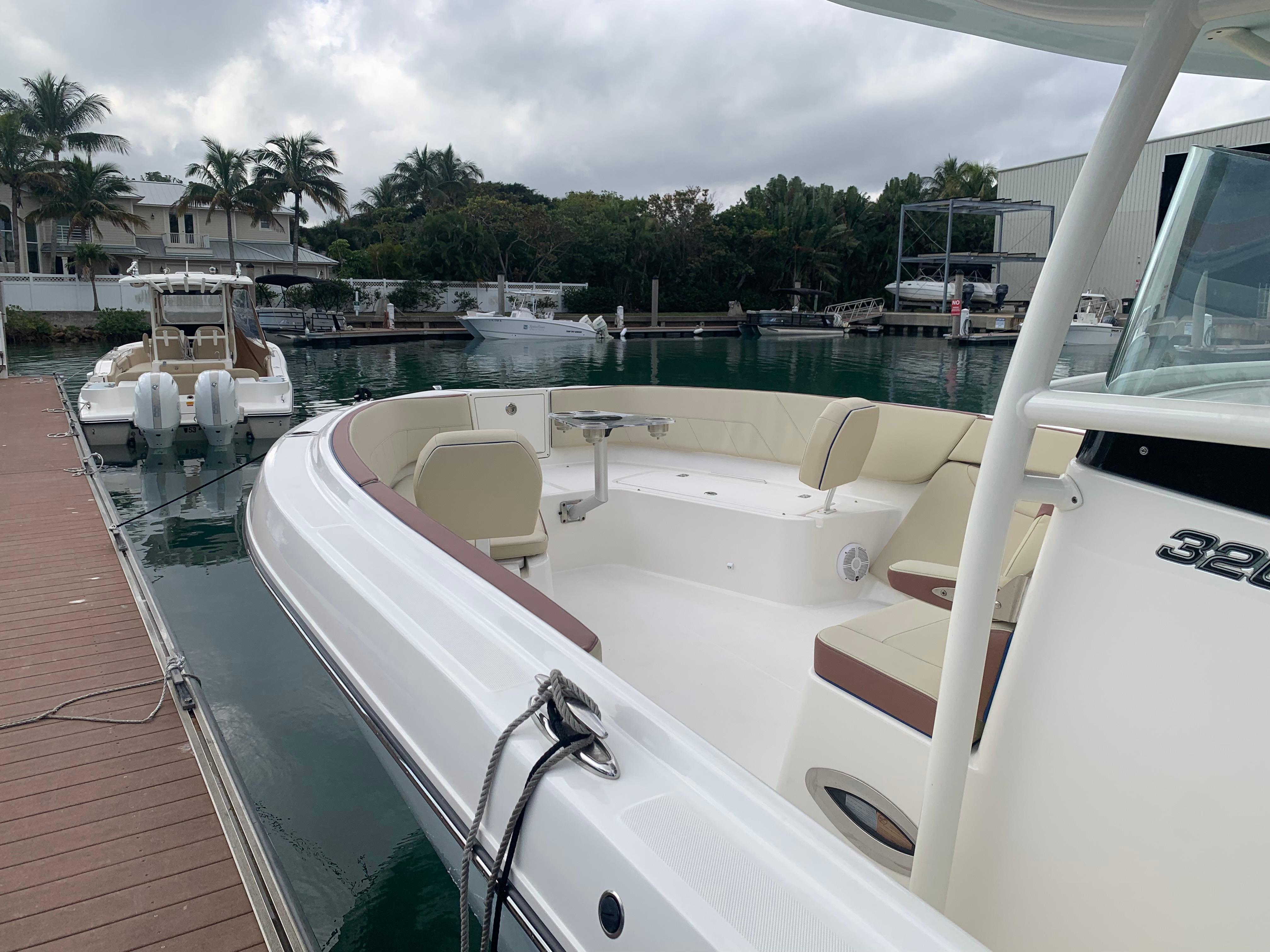 2019 Century 3200 Center Console boat docked at marina with seating area.