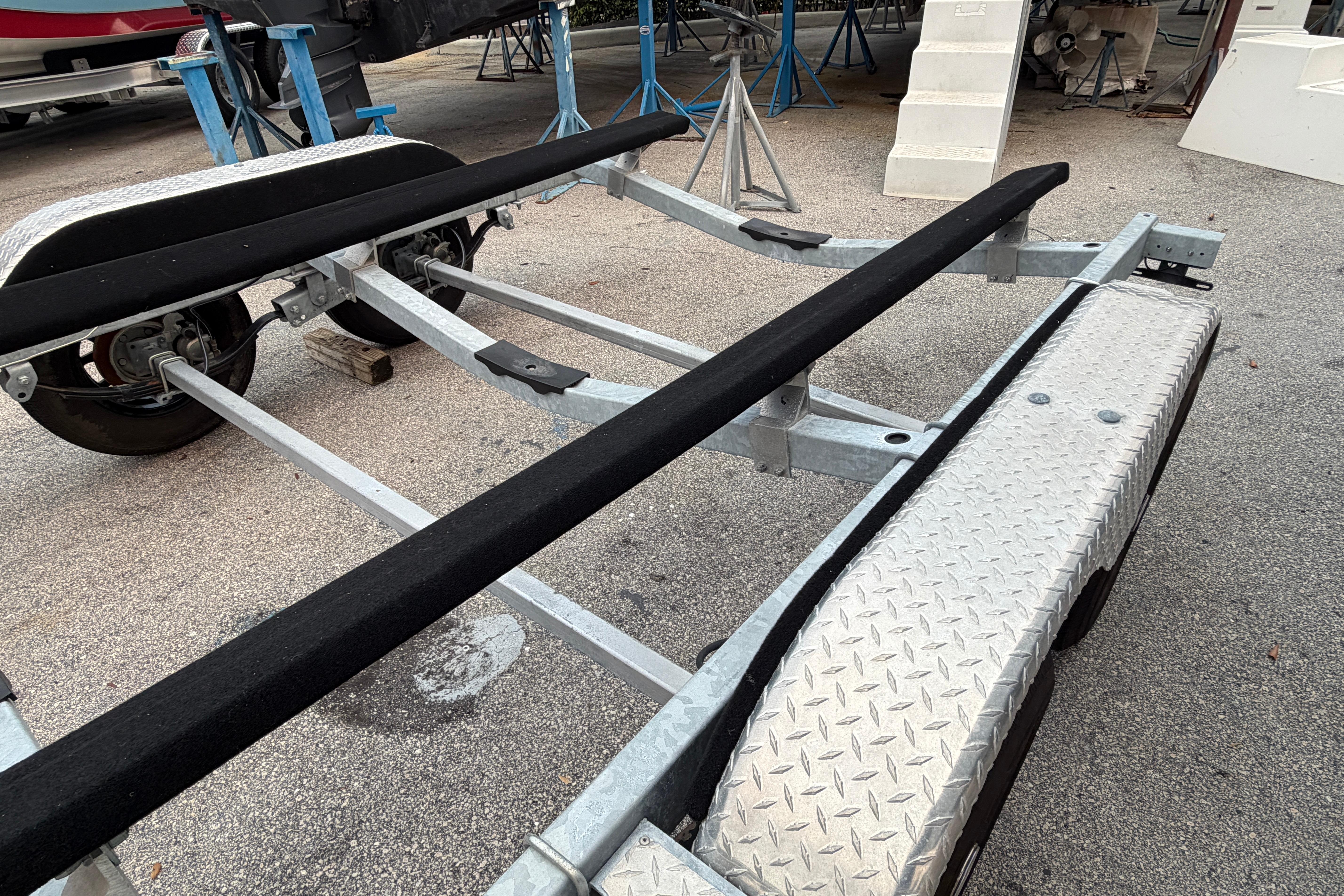 2024 SRT5000 boat trailer with dual axles and diamond plate fenders in a parking area.
