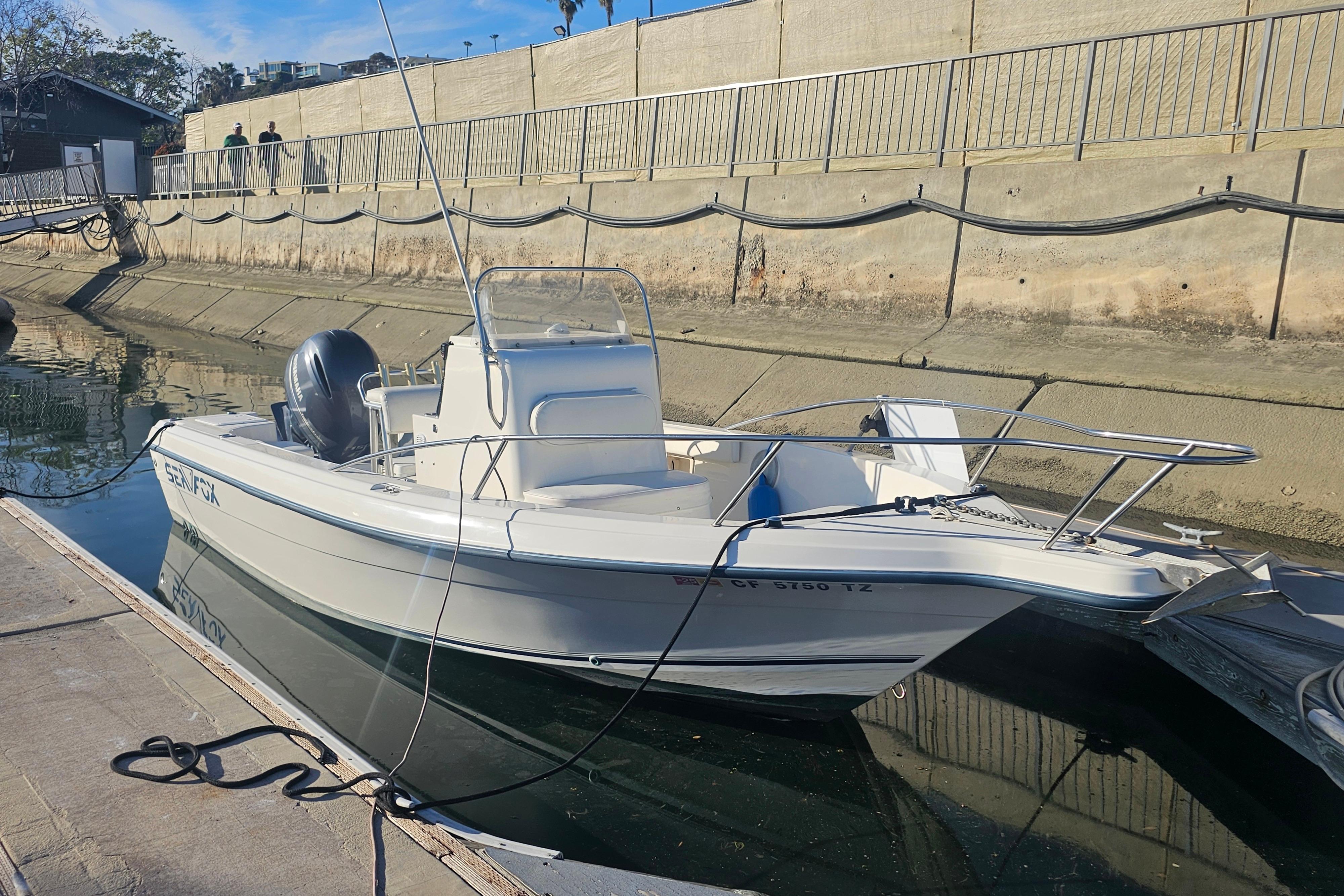 2002 Sea Fox 210 Center Console boat docked in a canal on a sunny day.