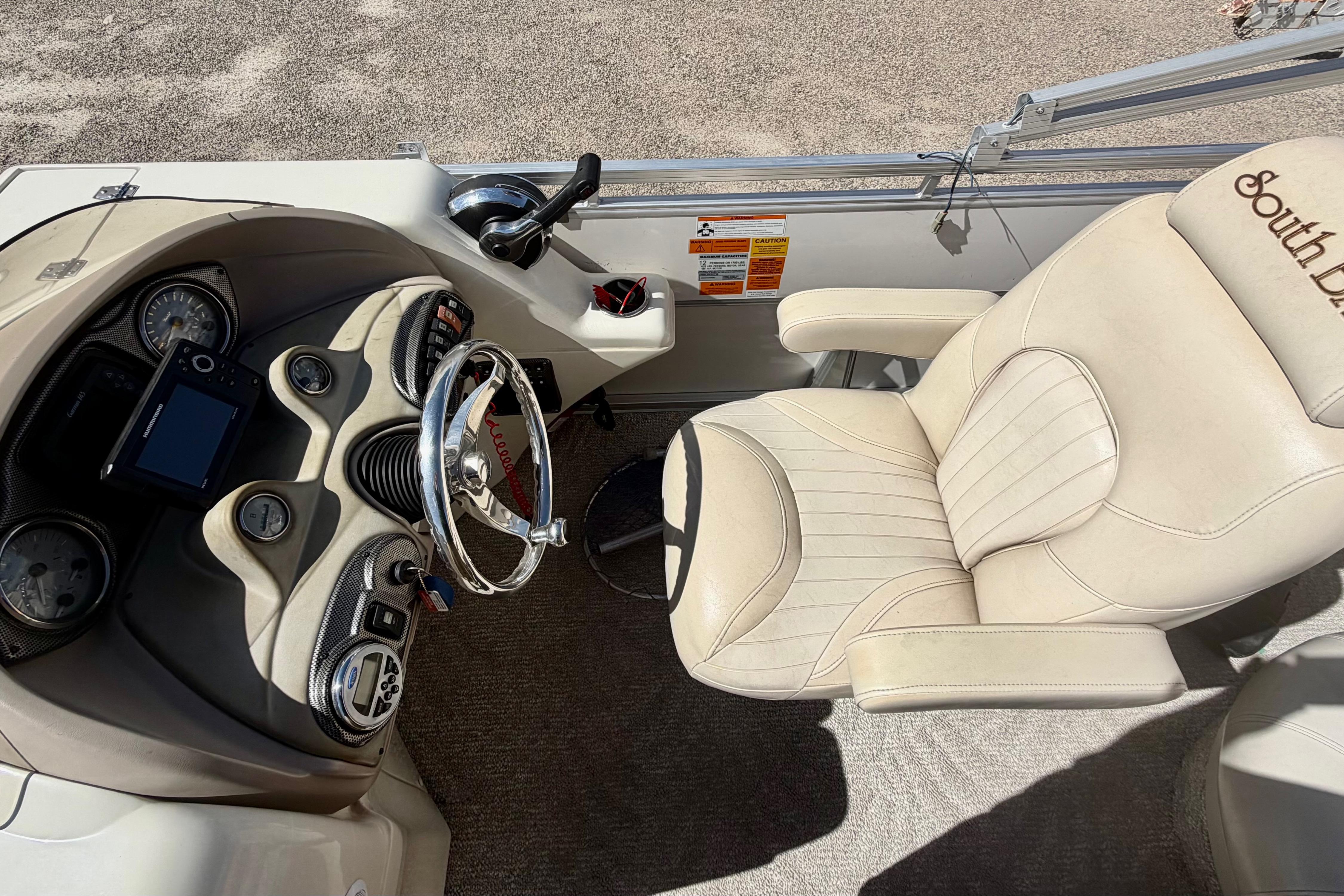 Captain's chair and helm of 2006 South Bay 925CR boat, featuring steering wheel and controls.