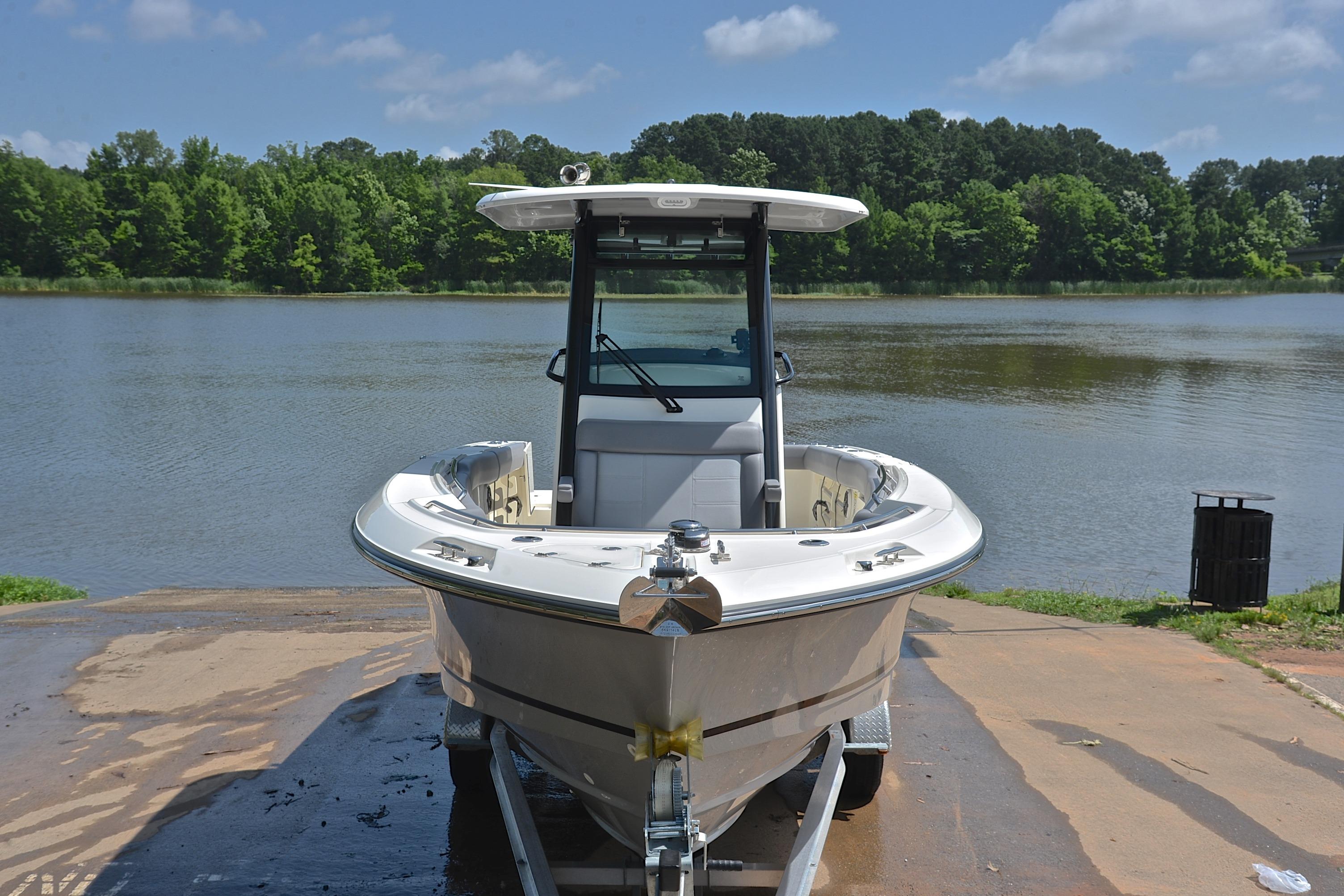 2024 Boston Whaler 250 Outrage boat on trailer by a scenic lake.