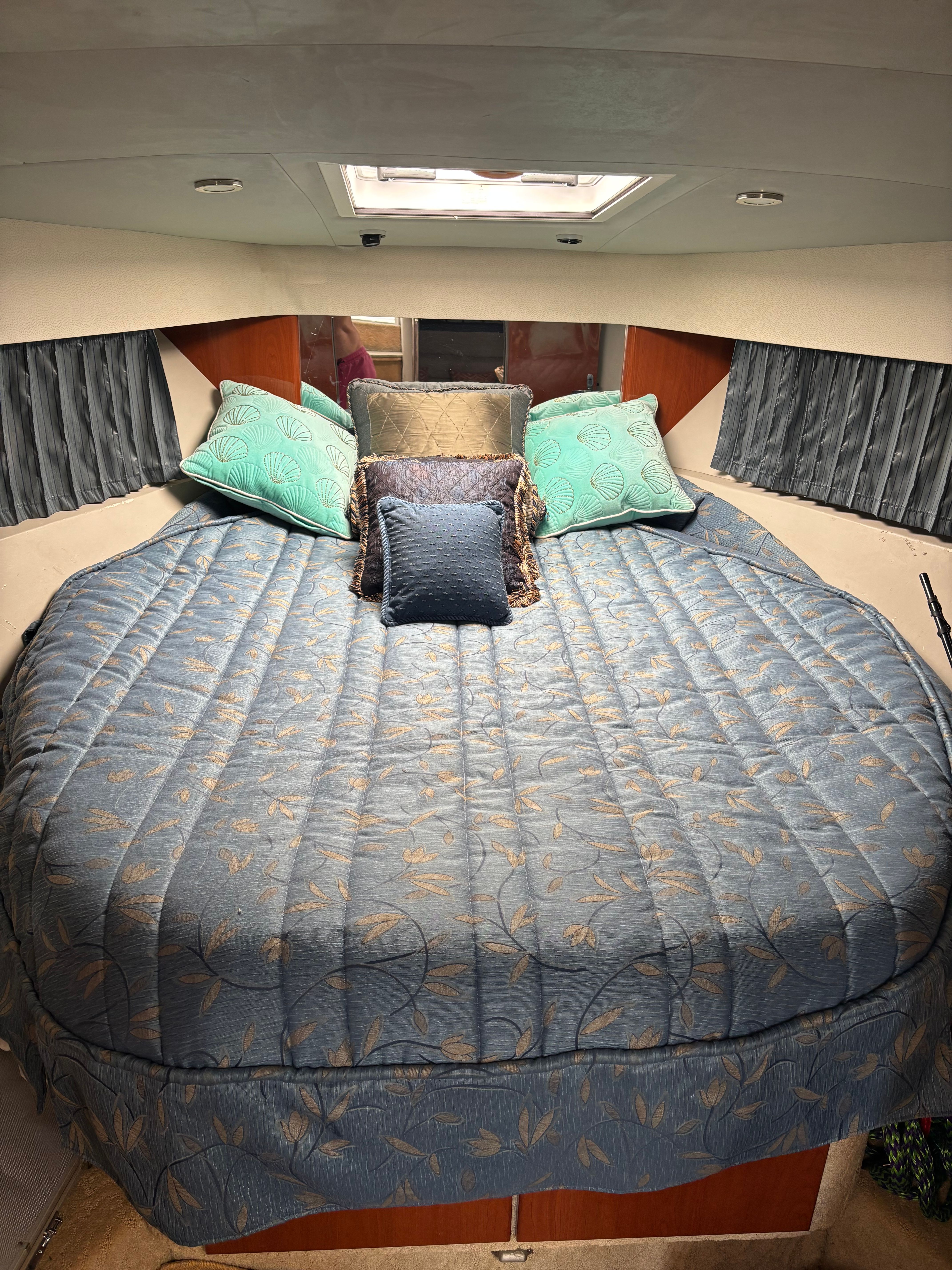 Cabin with a cozy bed and pillows, surrounded by curtains and skylights.