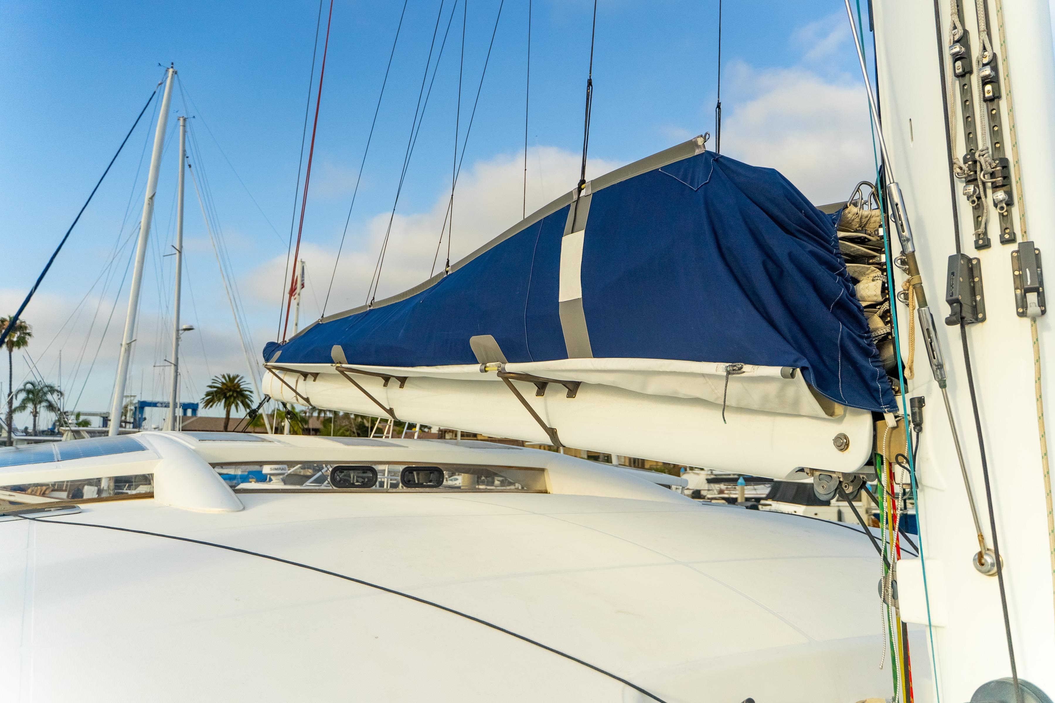 2009 Catana 65 sailboat with covered boom, docked in marina under blue sky.