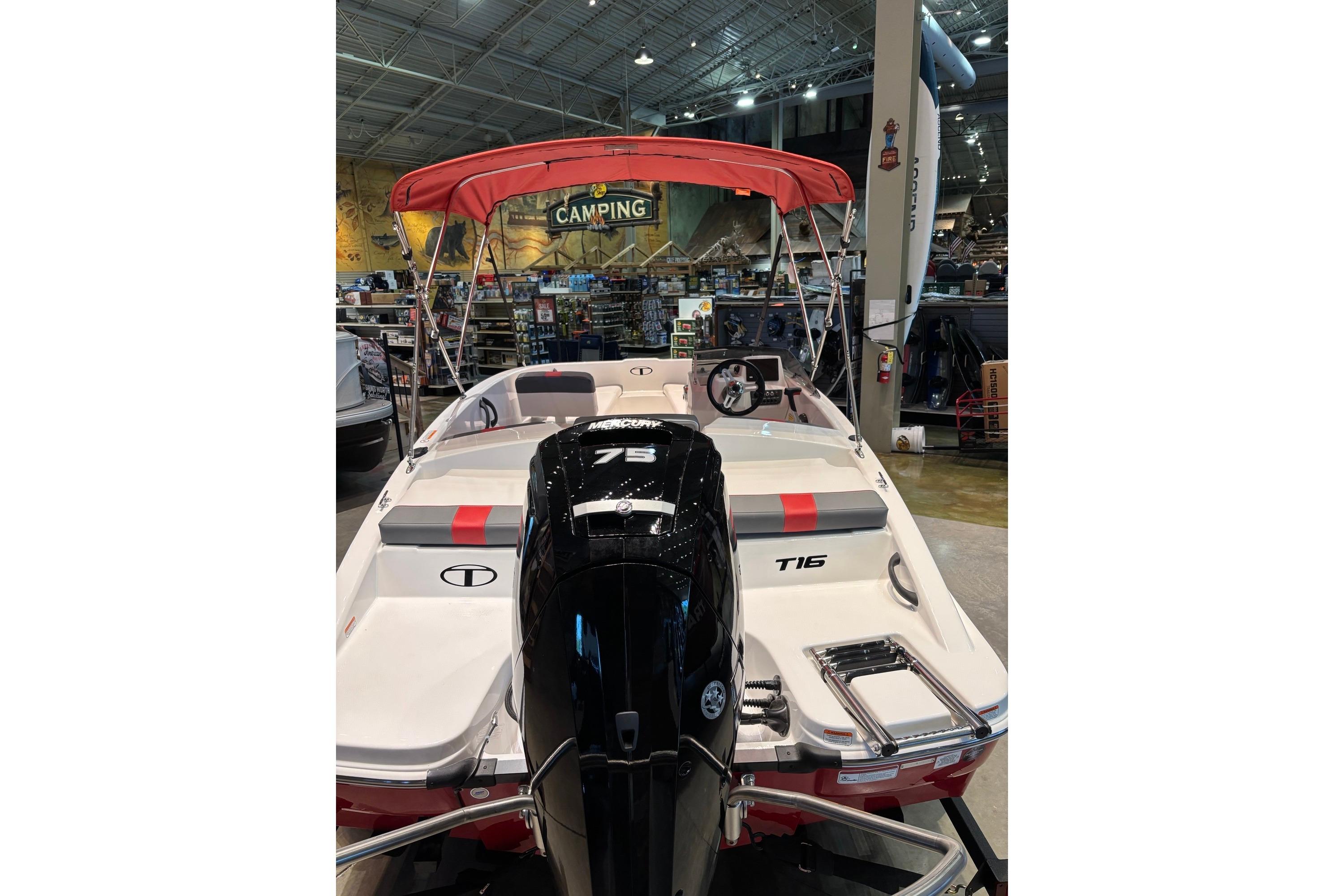 2026 Tahoe T16 boat with red canopy and Mercury 75 engine displayed indoors.