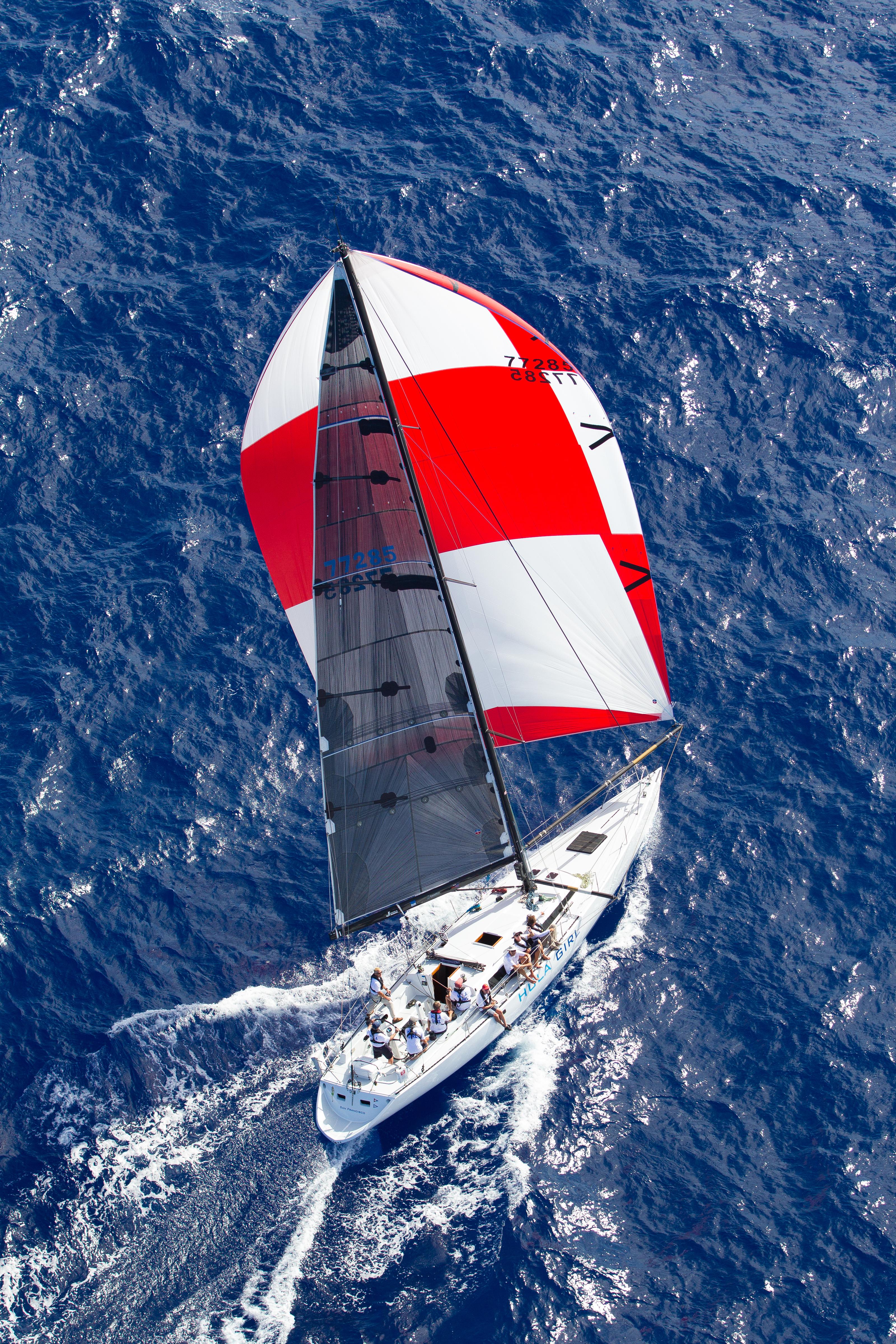 Aerial view of 1980 Santa Cruz SC 50 sailboat with red and white spinnaker on open sea.