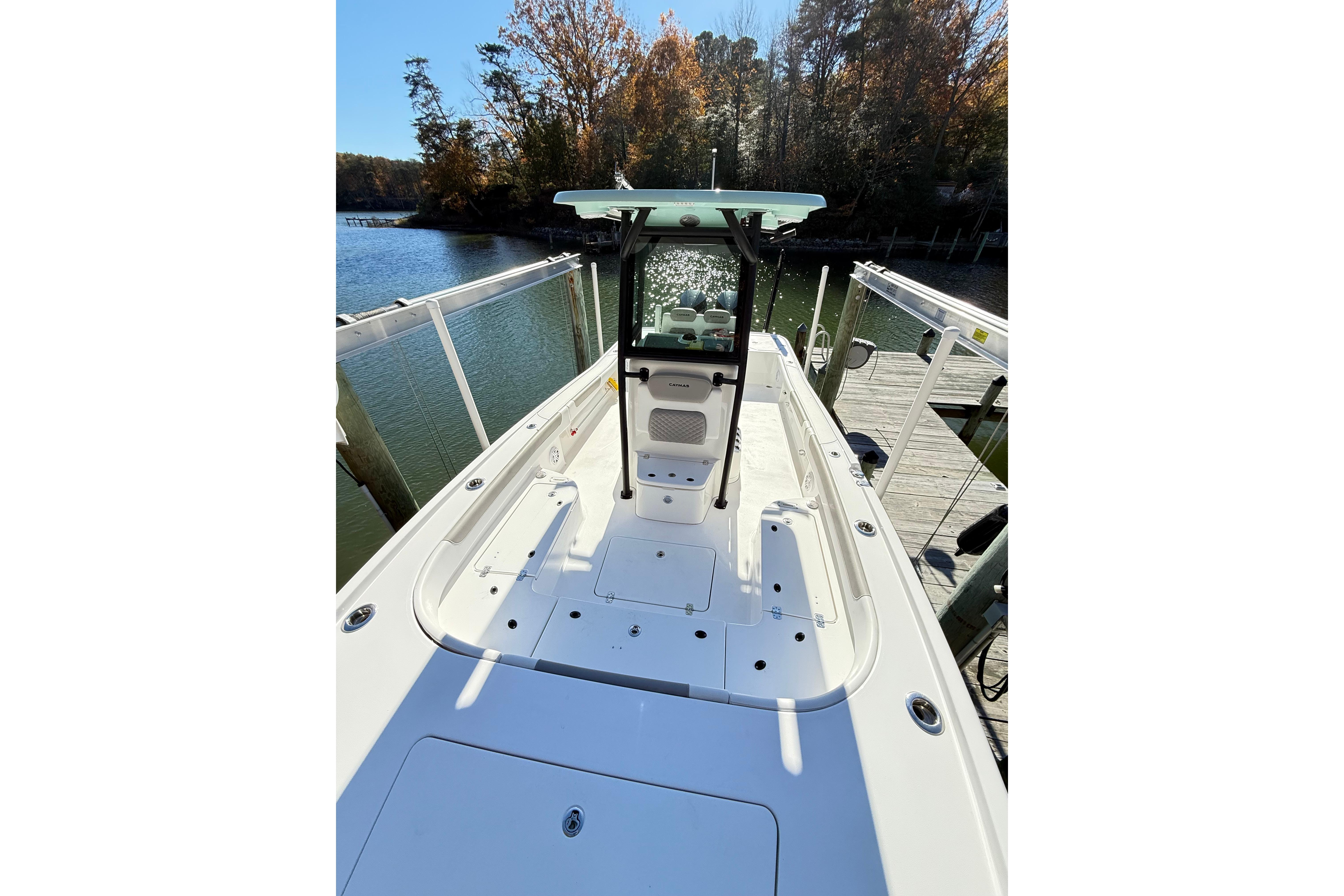 2023 Caymas 281 HB boat docked by a scenic waterfront with autumn trees.