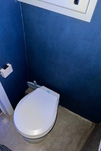 Modern bathroom with blue walls, featuring a white toilet and toilet paper holder.