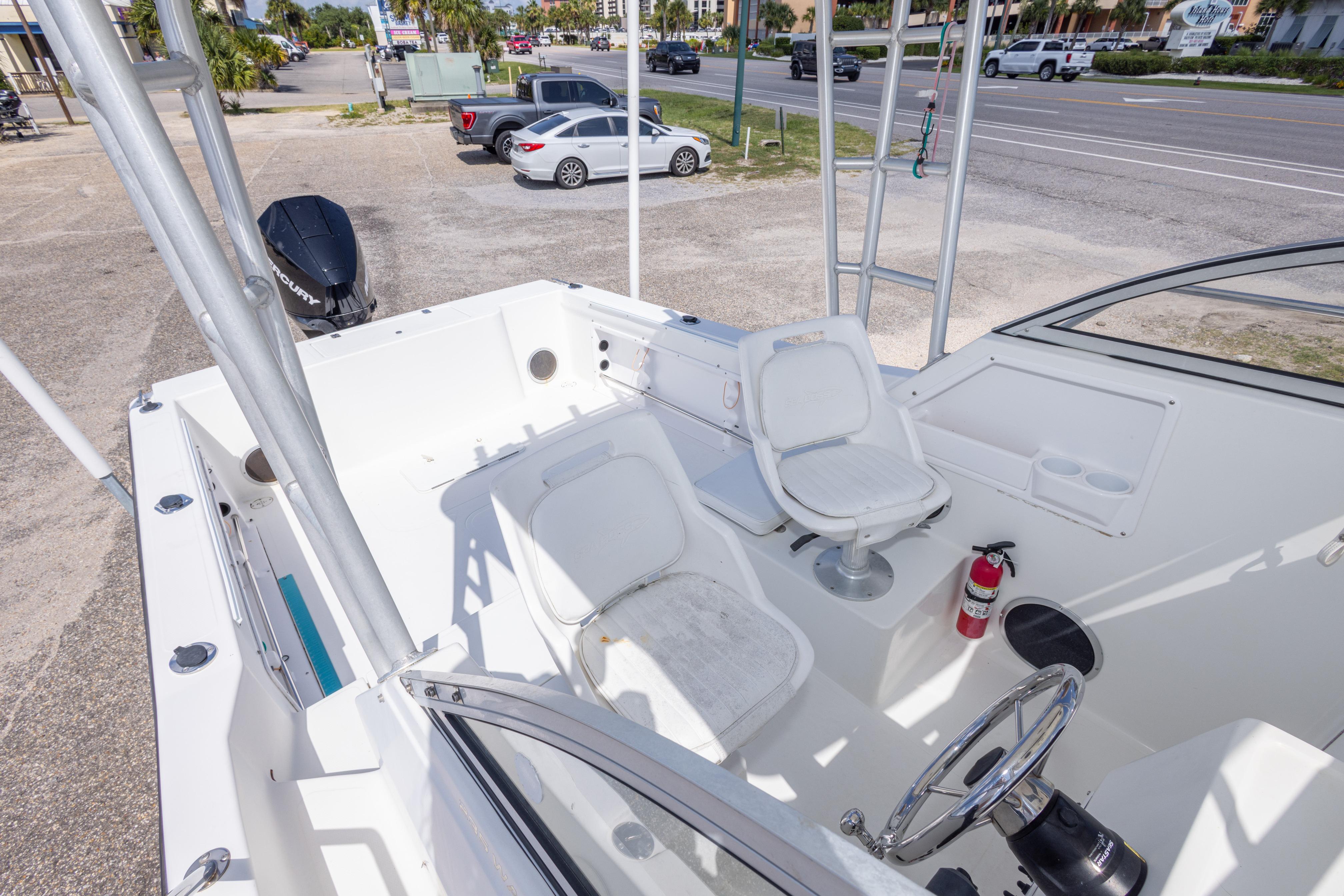 2007 Sea Boss 235 Walkaround boat interior with seating and steering wheel, parked near a road.