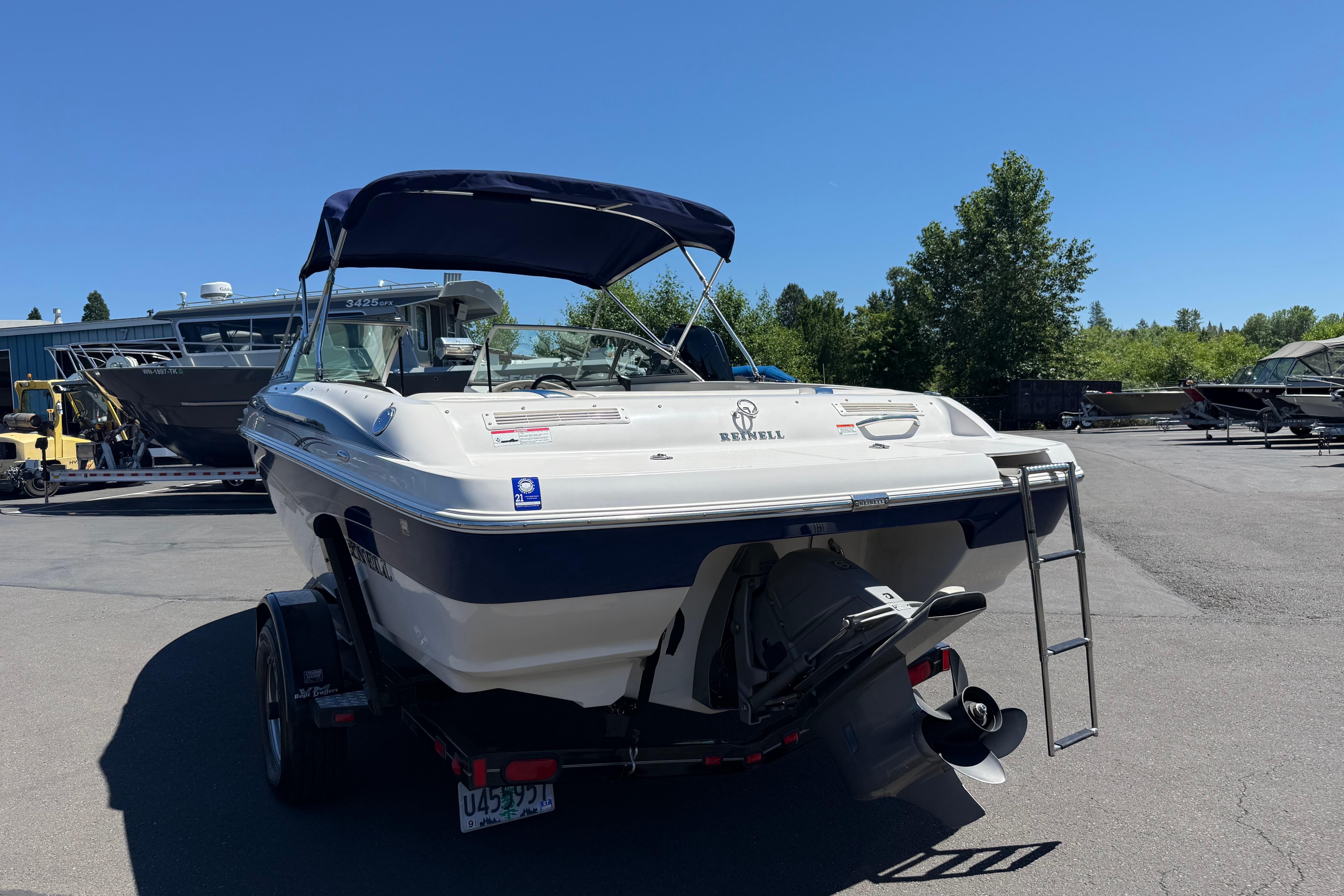 2011 Reinell 197 boat with canopy, parked on trailer in sunny outdoor setting.