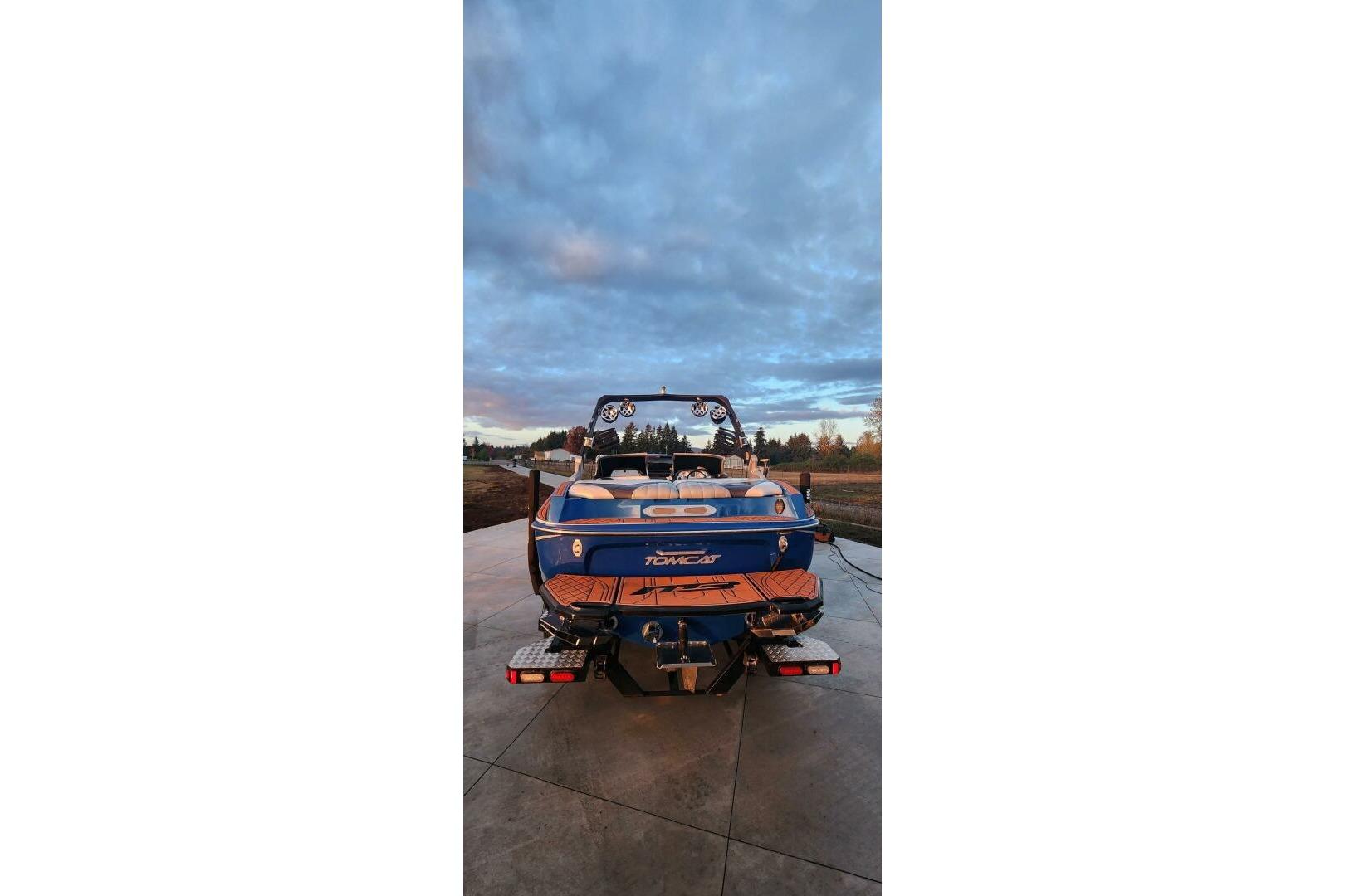 2017 MB F21 boat with blue and orange design, parked on concrete under a cloudy sky.