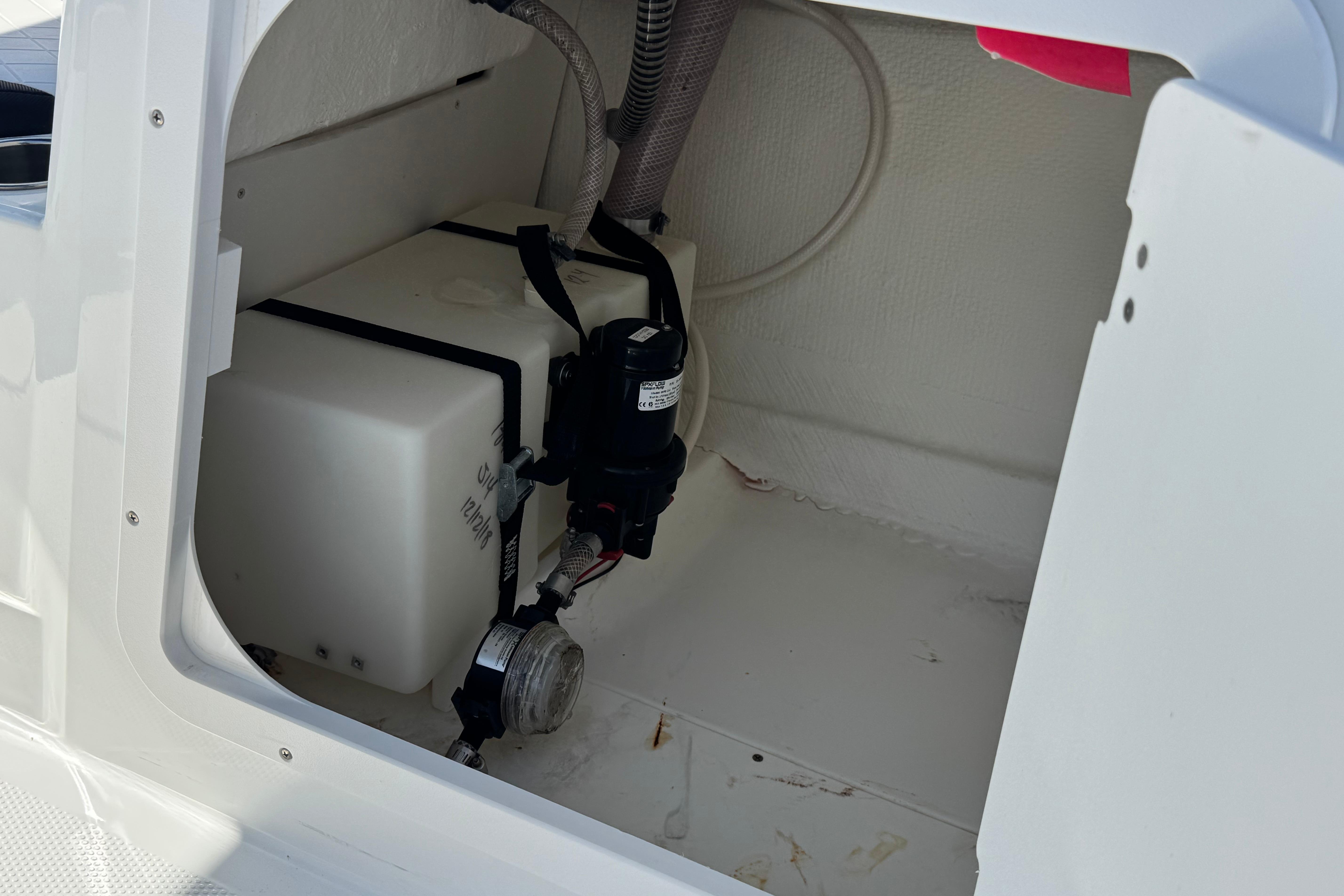 Storage compartment of a 2019 Tahoe 2150 boat, featuring a secured water tank and pump system.